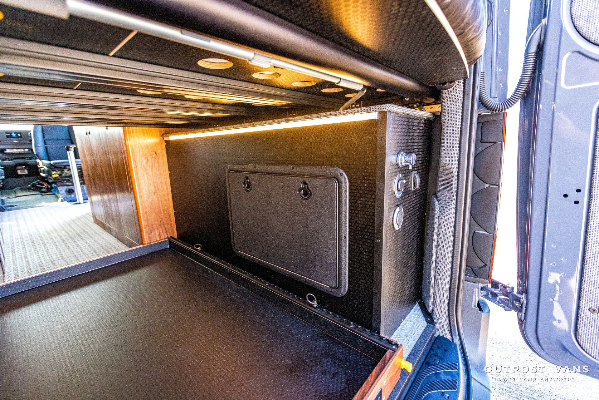 The inside of a van with a bed and a drawer underneath it.