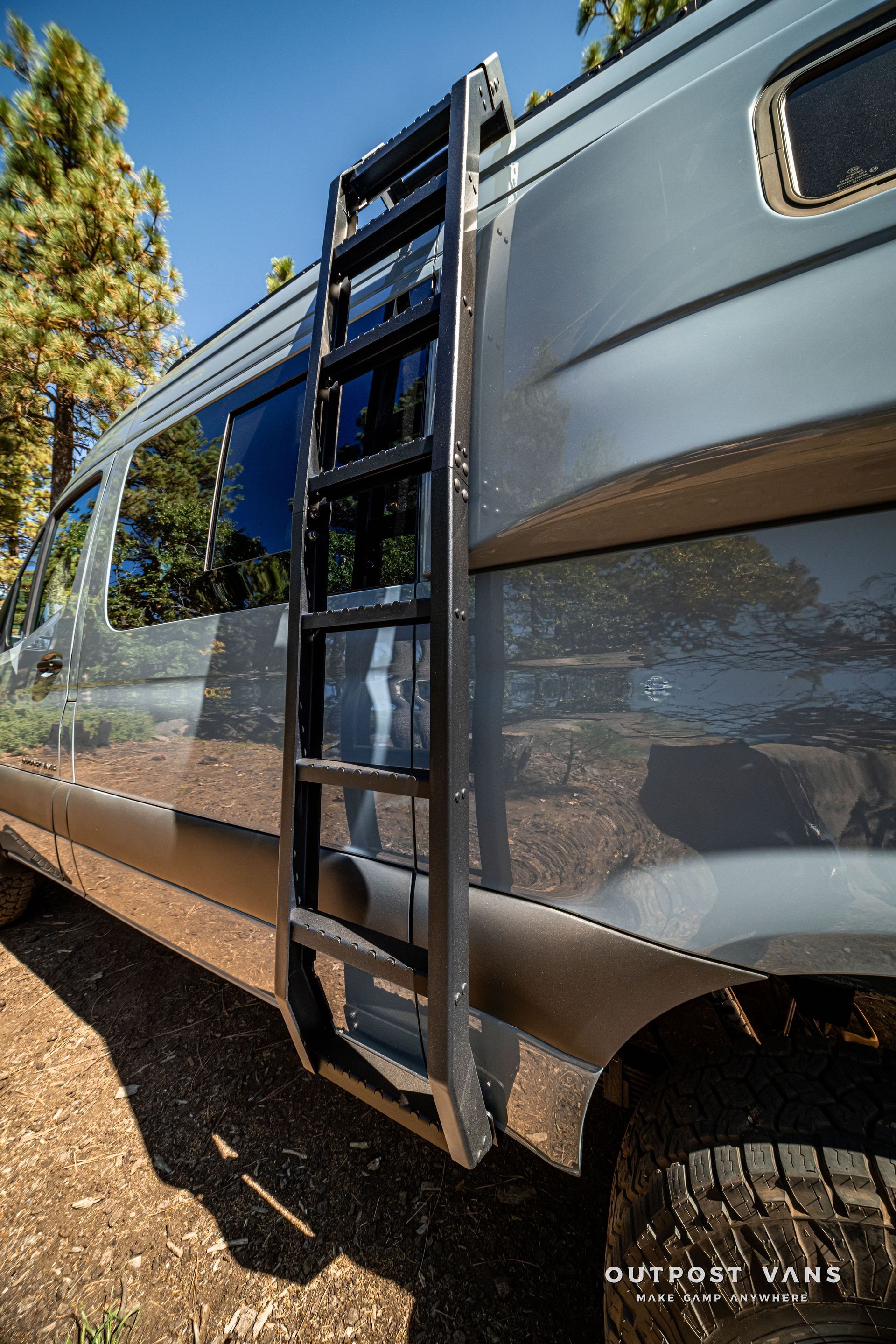 Sprinter Black ladder attached to side of blue van parked outdoors.