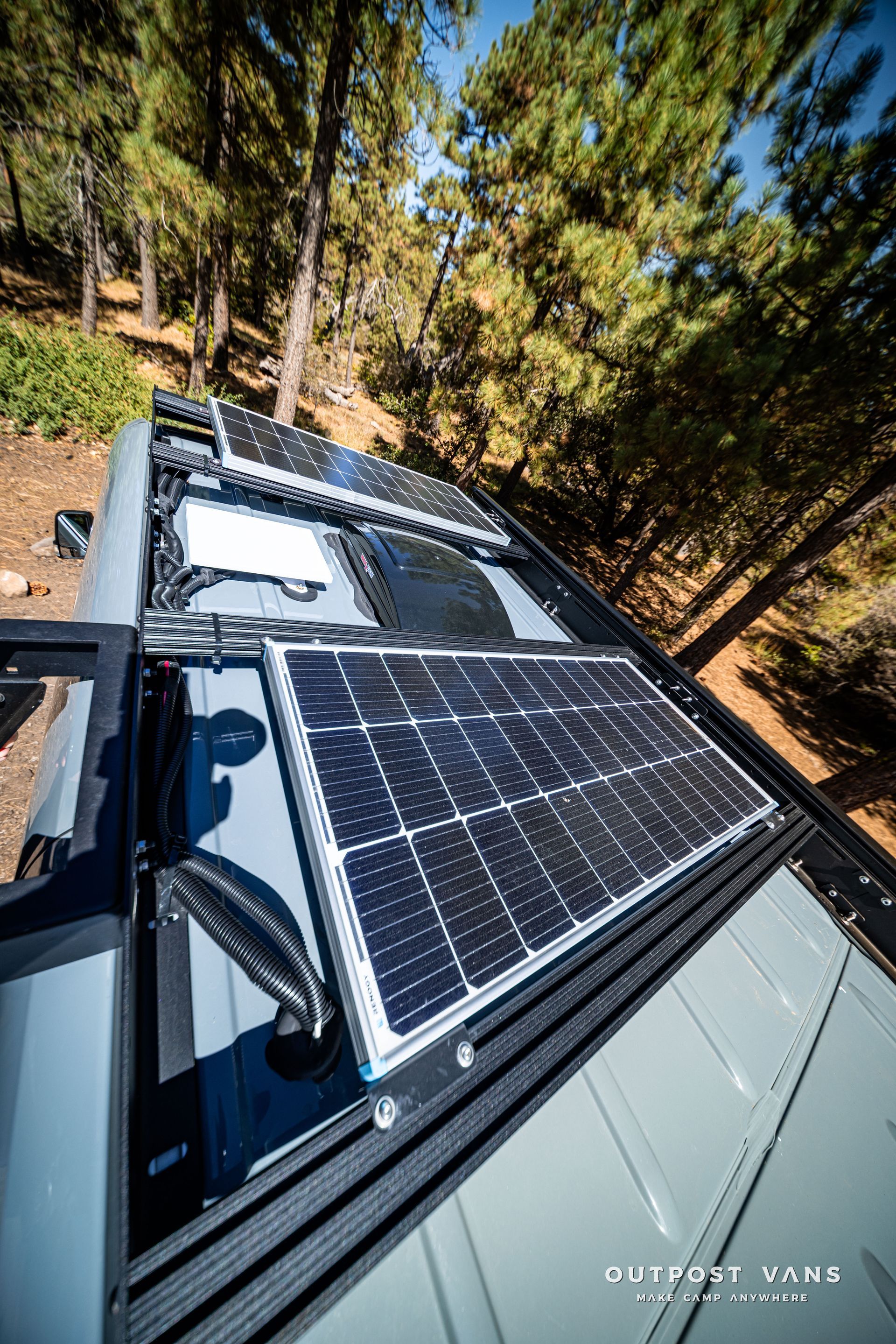 Sprinter Solar panels on a van roof in a forest setting, surrounded by trees and sunlight.