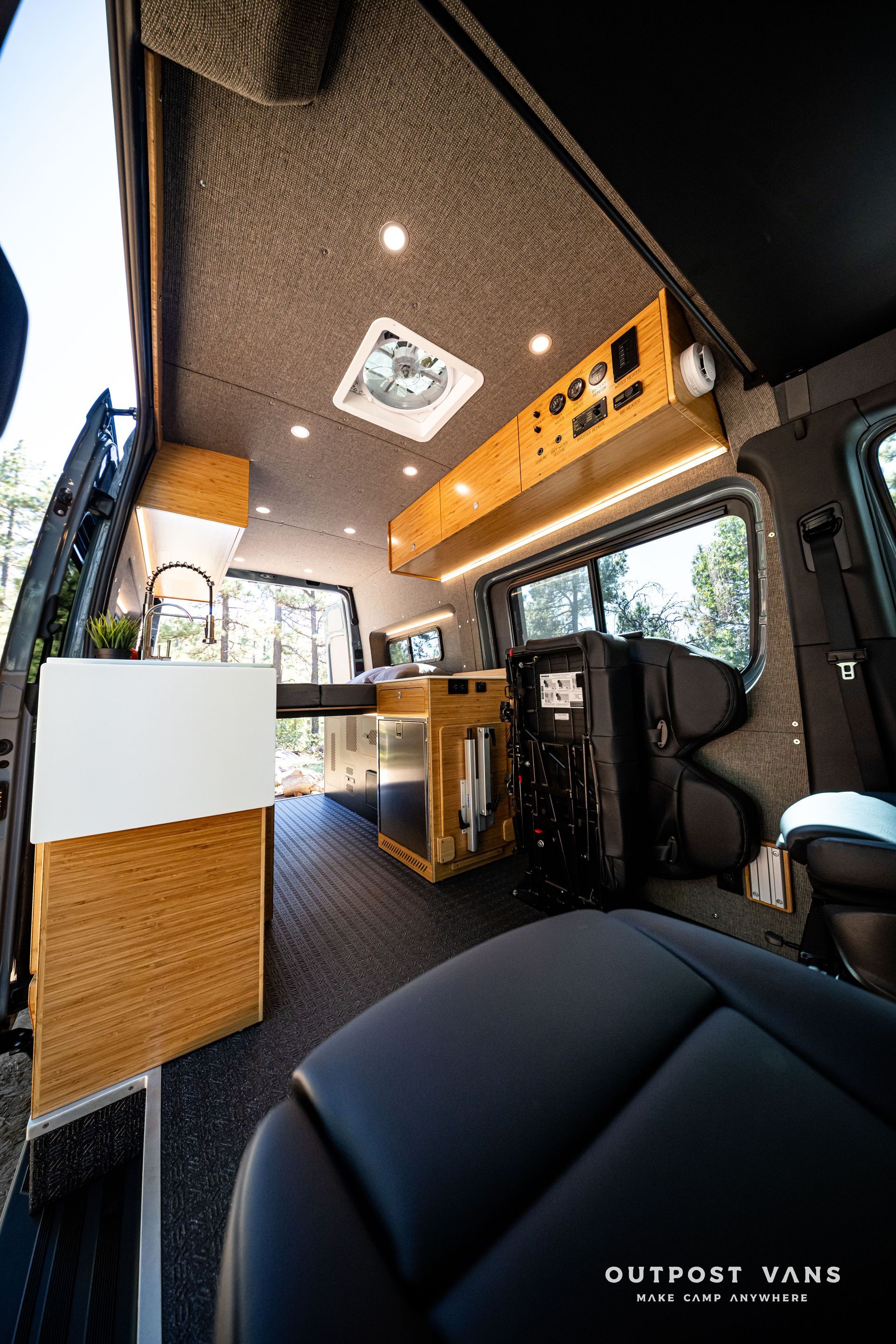 Sprinter Interior of a camper van with wood accents, black leather seats, and overhead lights.