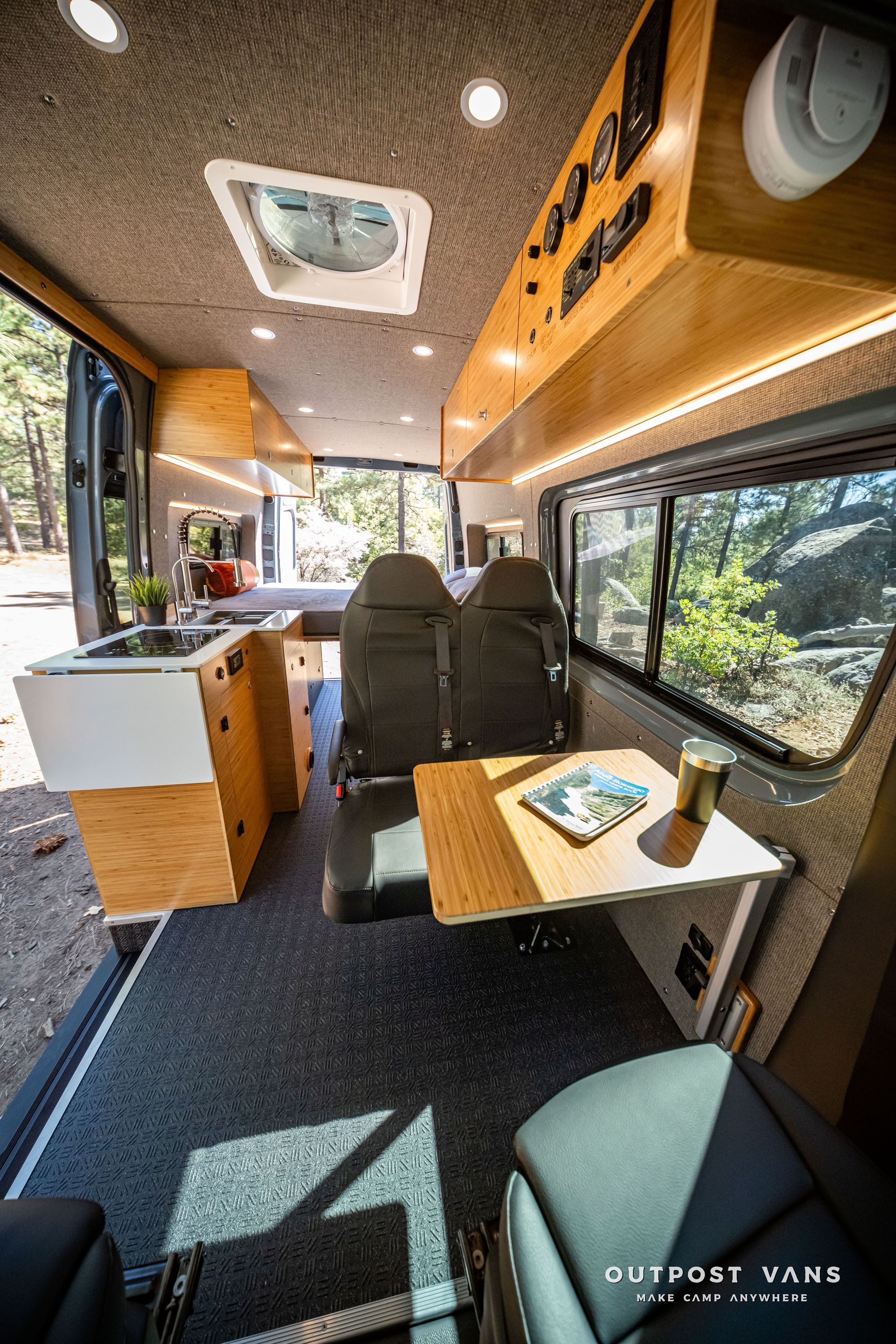 Sprinter Interior of a van converted for living: kitchen, seating area with table, storage, and windows.
