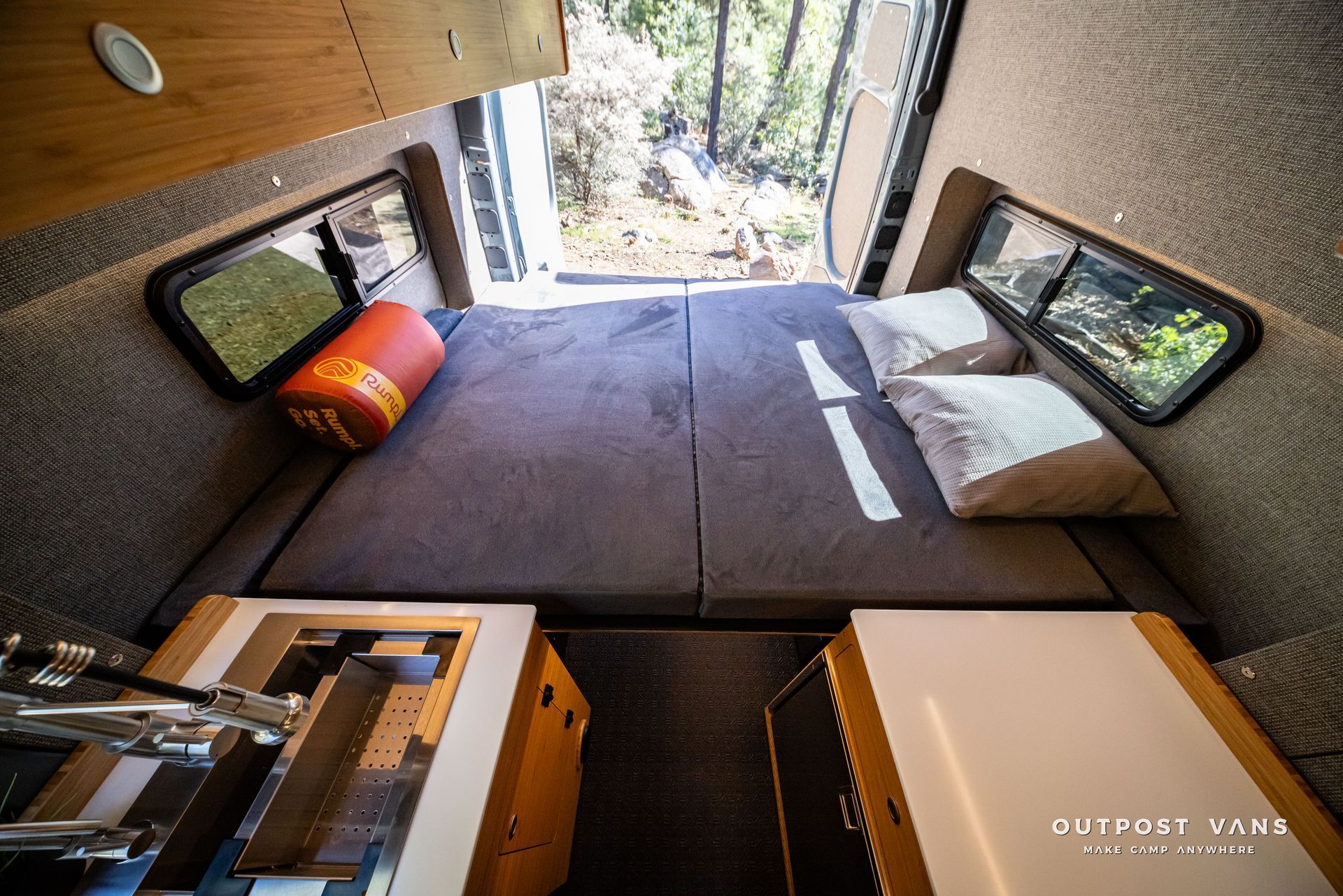 Sprinter Interior of a camper van with a bed, two windows, and a counter space.