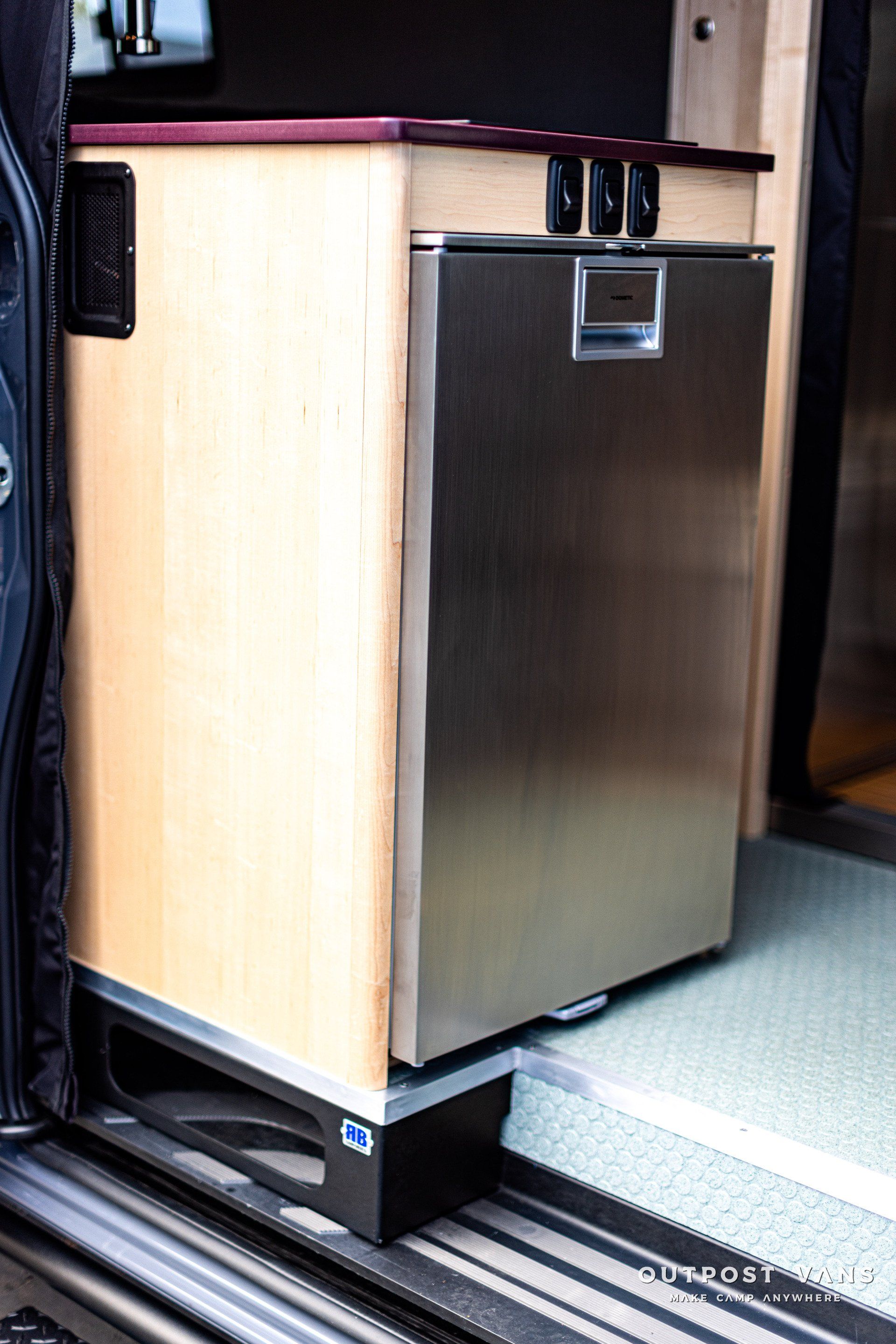 A stainless steel refrigerator is sitting in the back of a van.