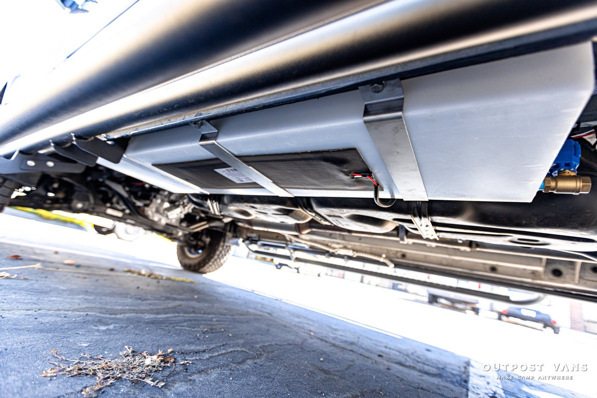 The underside of a car with a large tank underneath it.