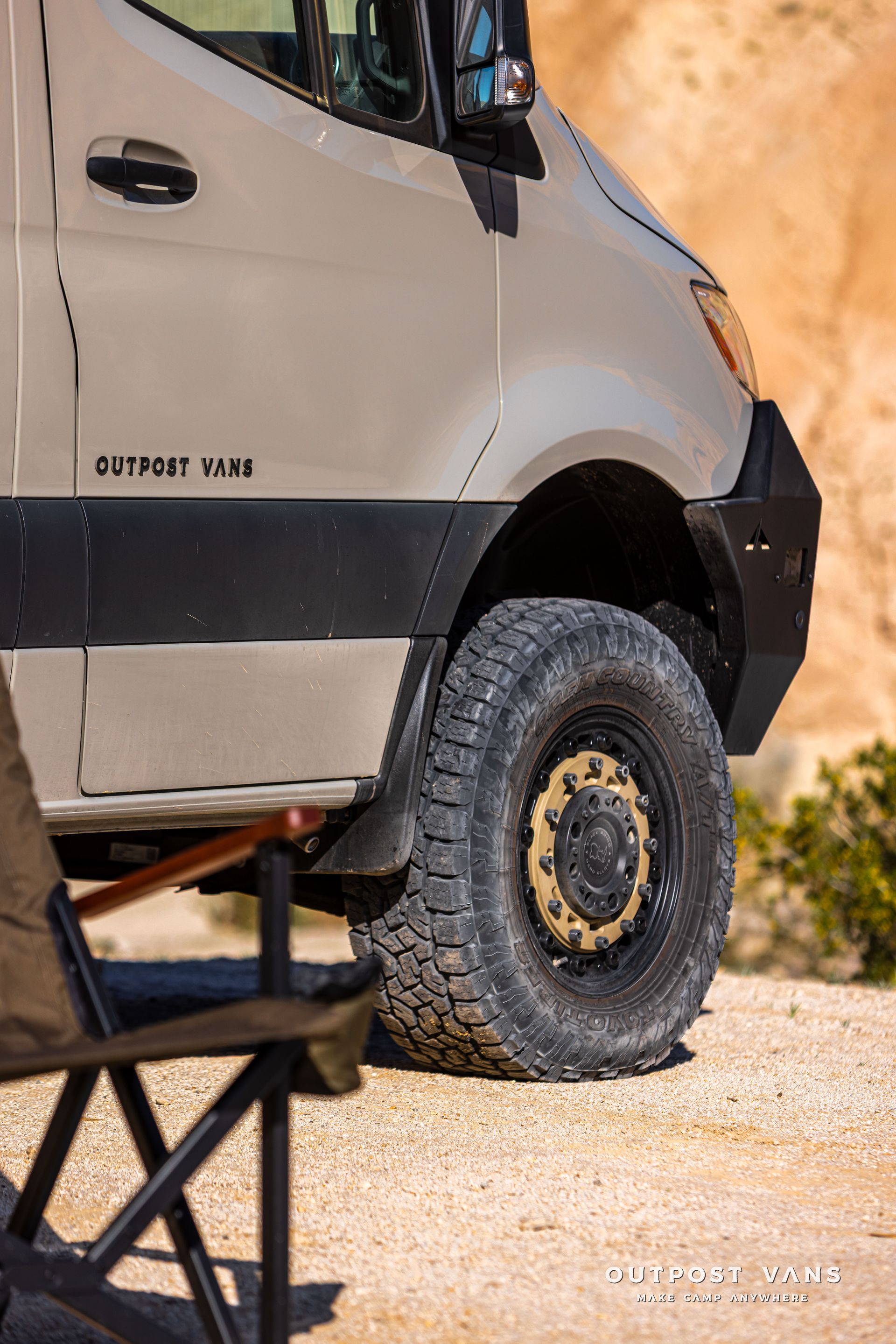 Off-road van with large tires parked on rocky desert ground