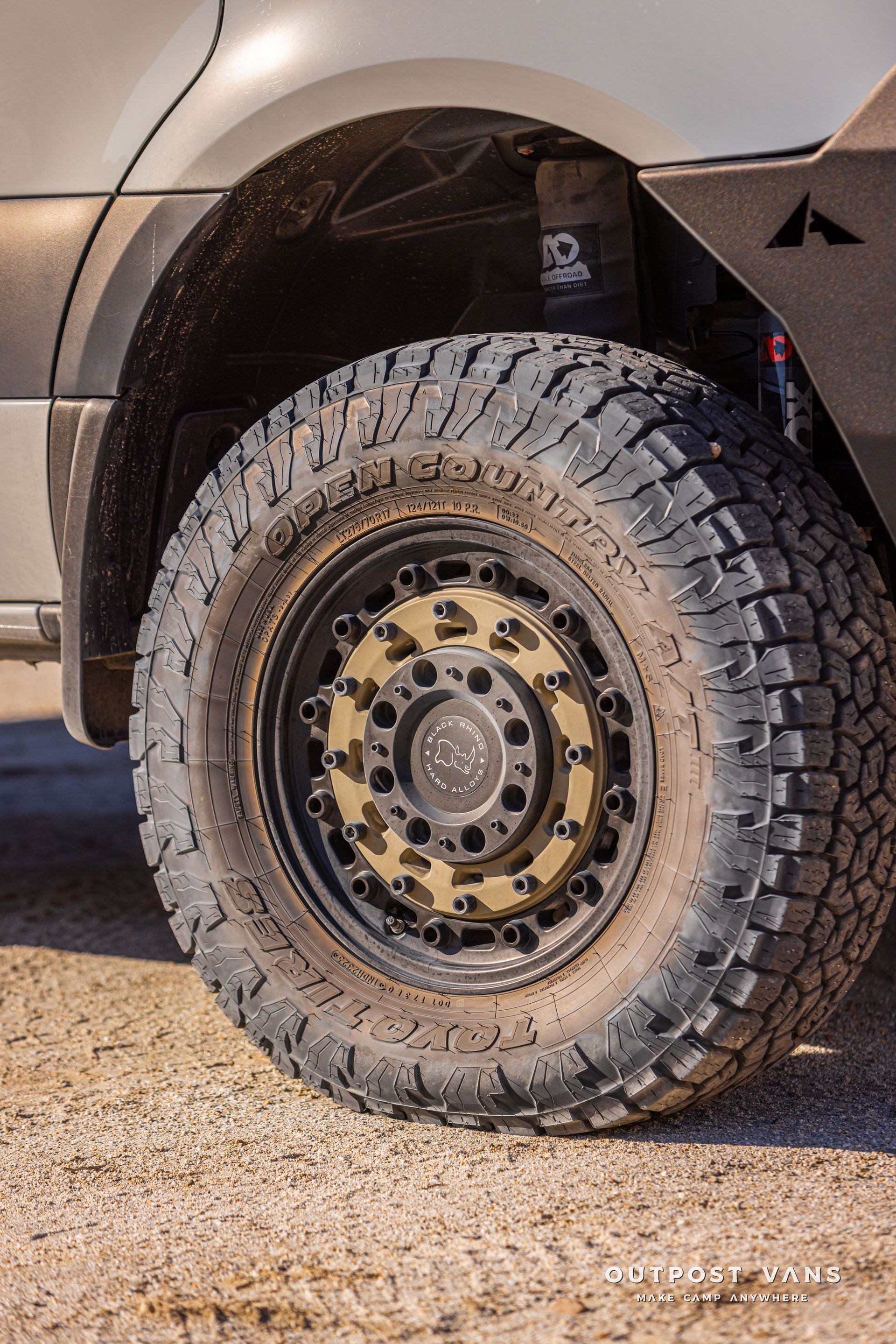 Off-road truck tire with black steel rim on a gravel surface