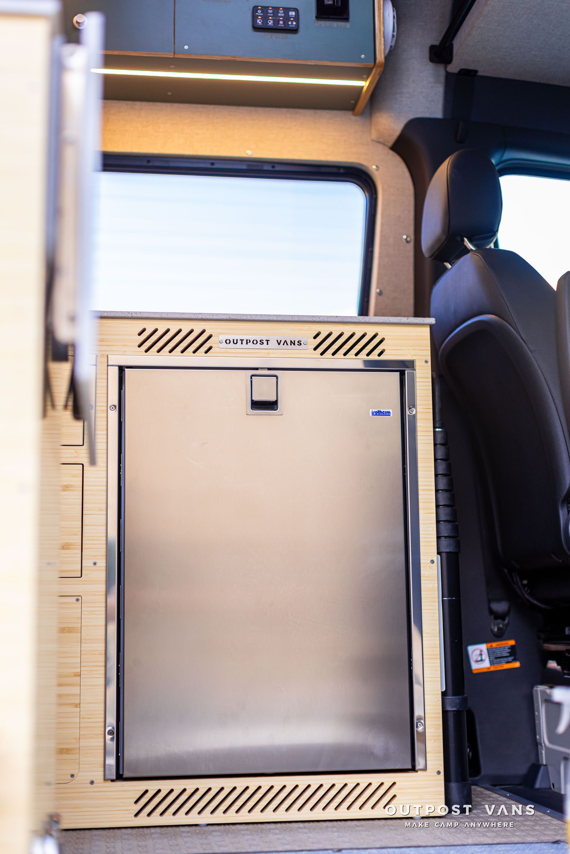 Passenger van interior with a large stainless steel storage cabinet beside a black seat.