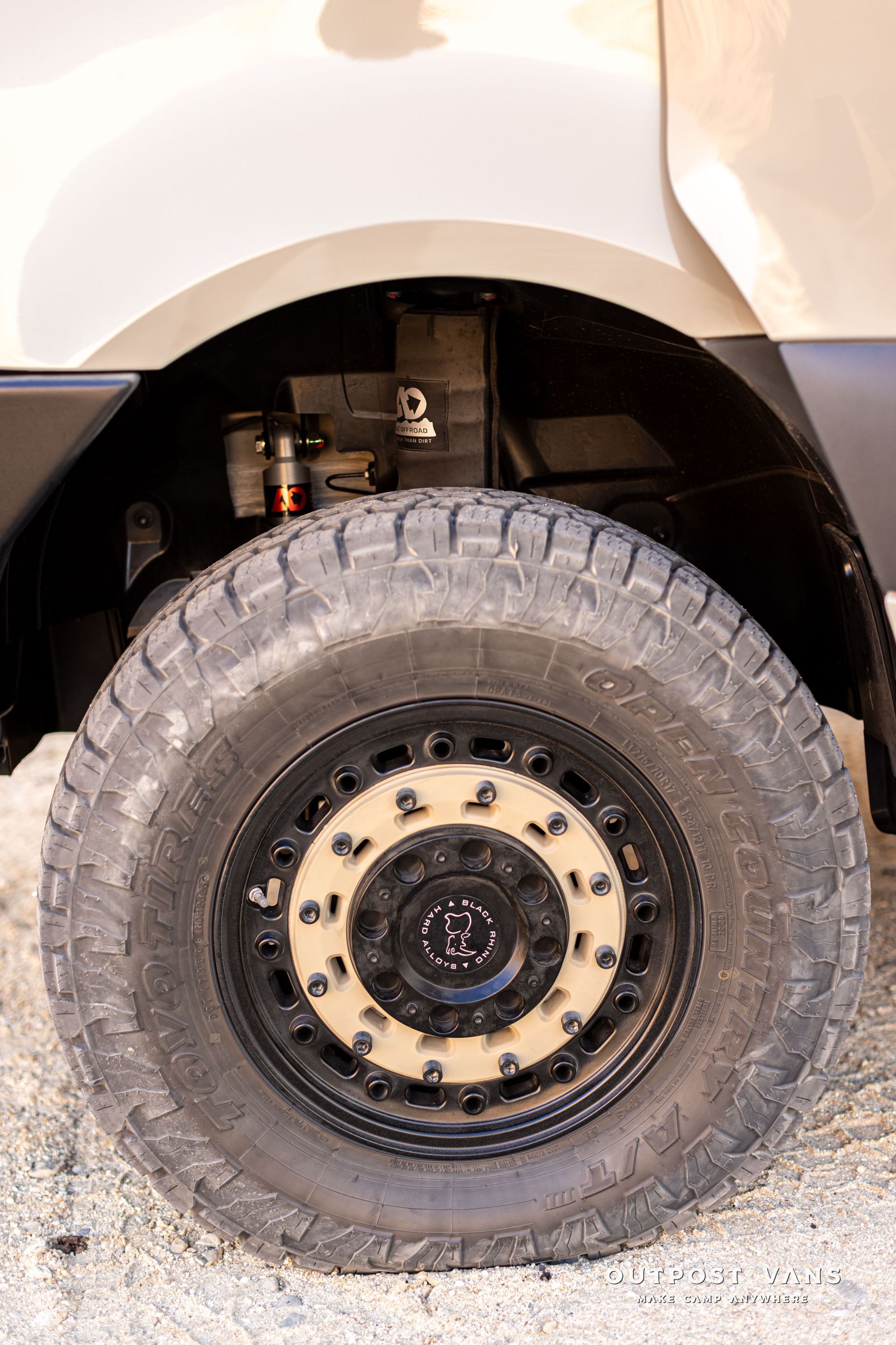 Close-up of a vehicle’s front wheel and tire under a white fender.