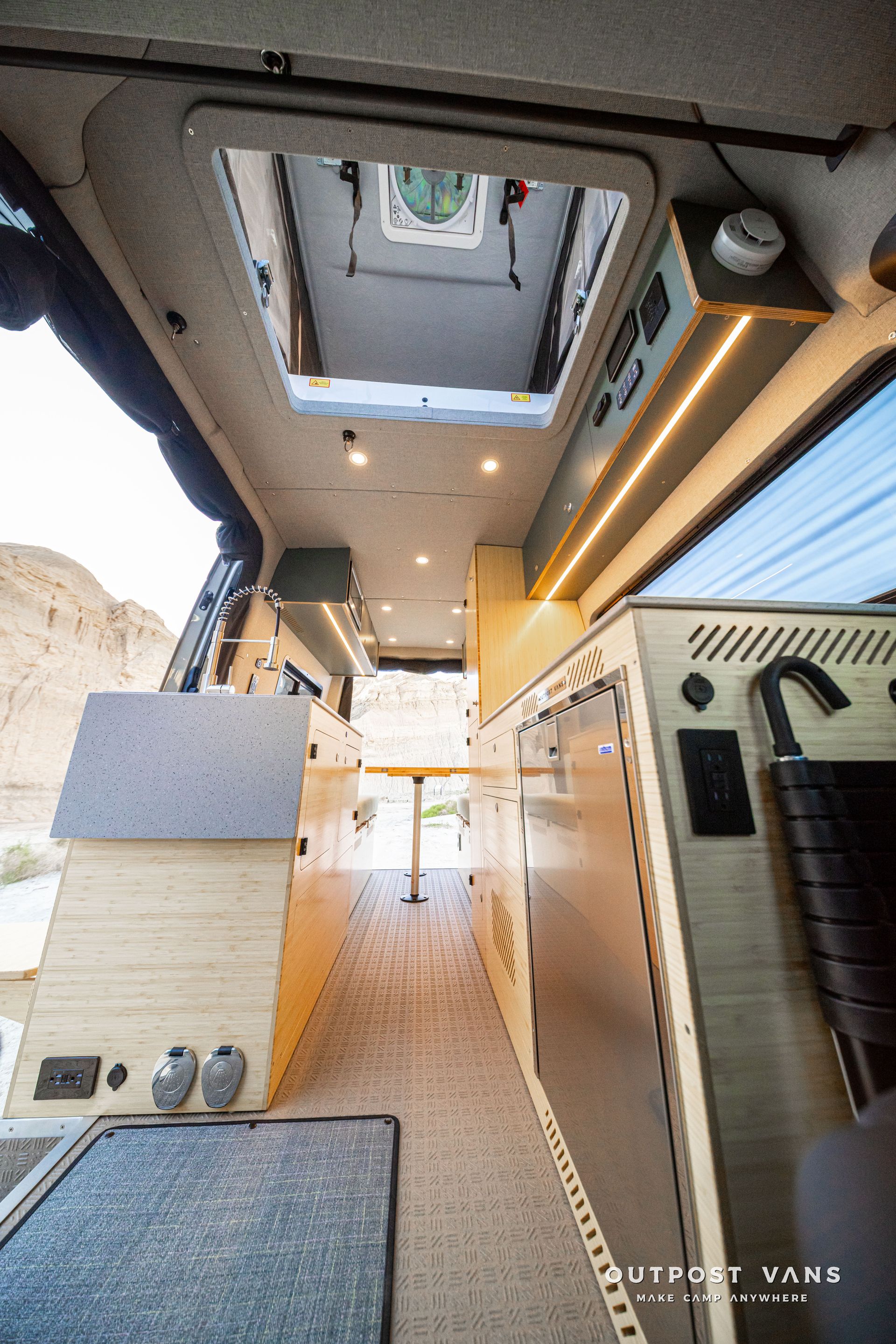 Interior of a modern camper van with skylight, wood accents, and a narrow aisle.