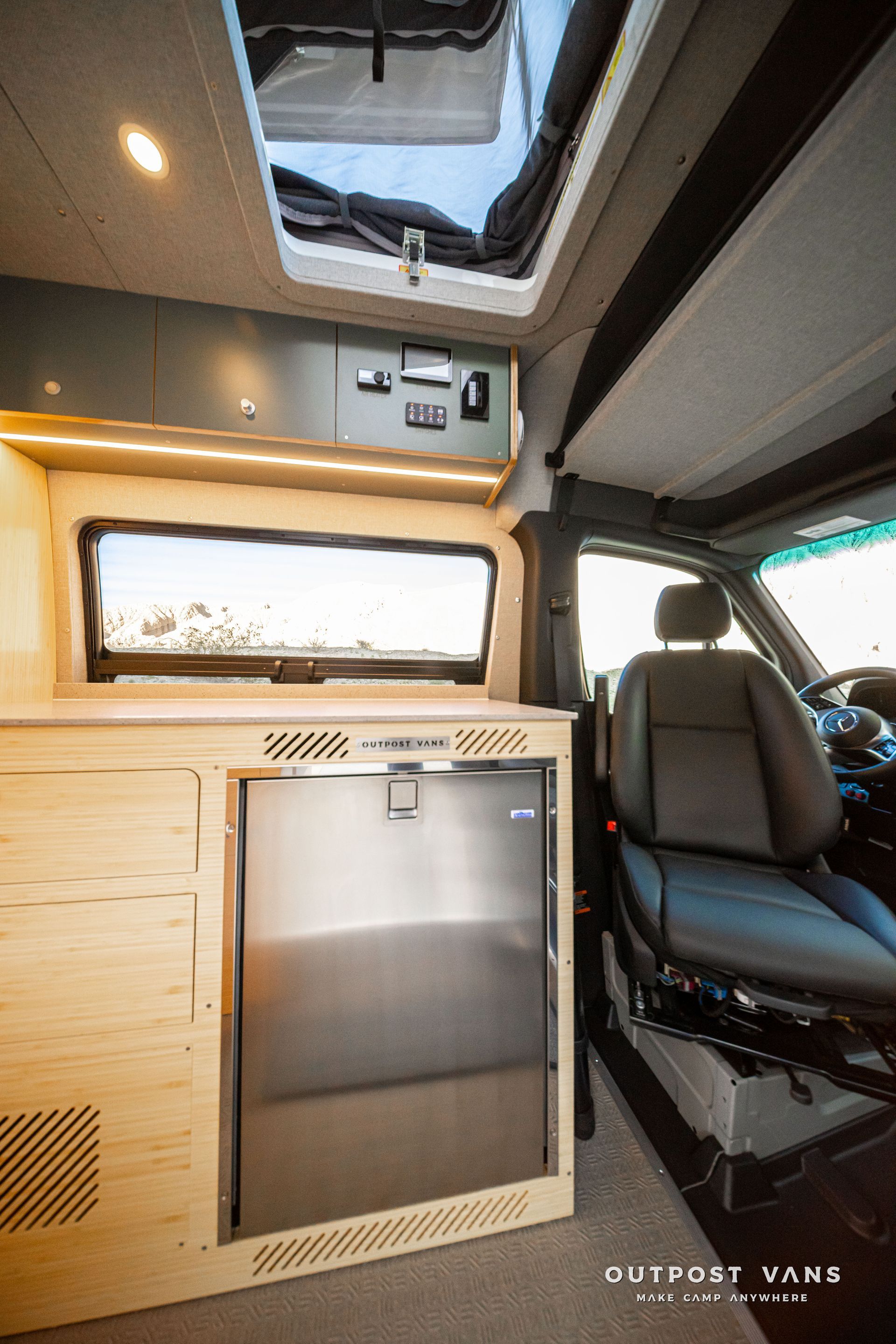 Compact van interior with wood cabinets, skylight, and front passenger seat.