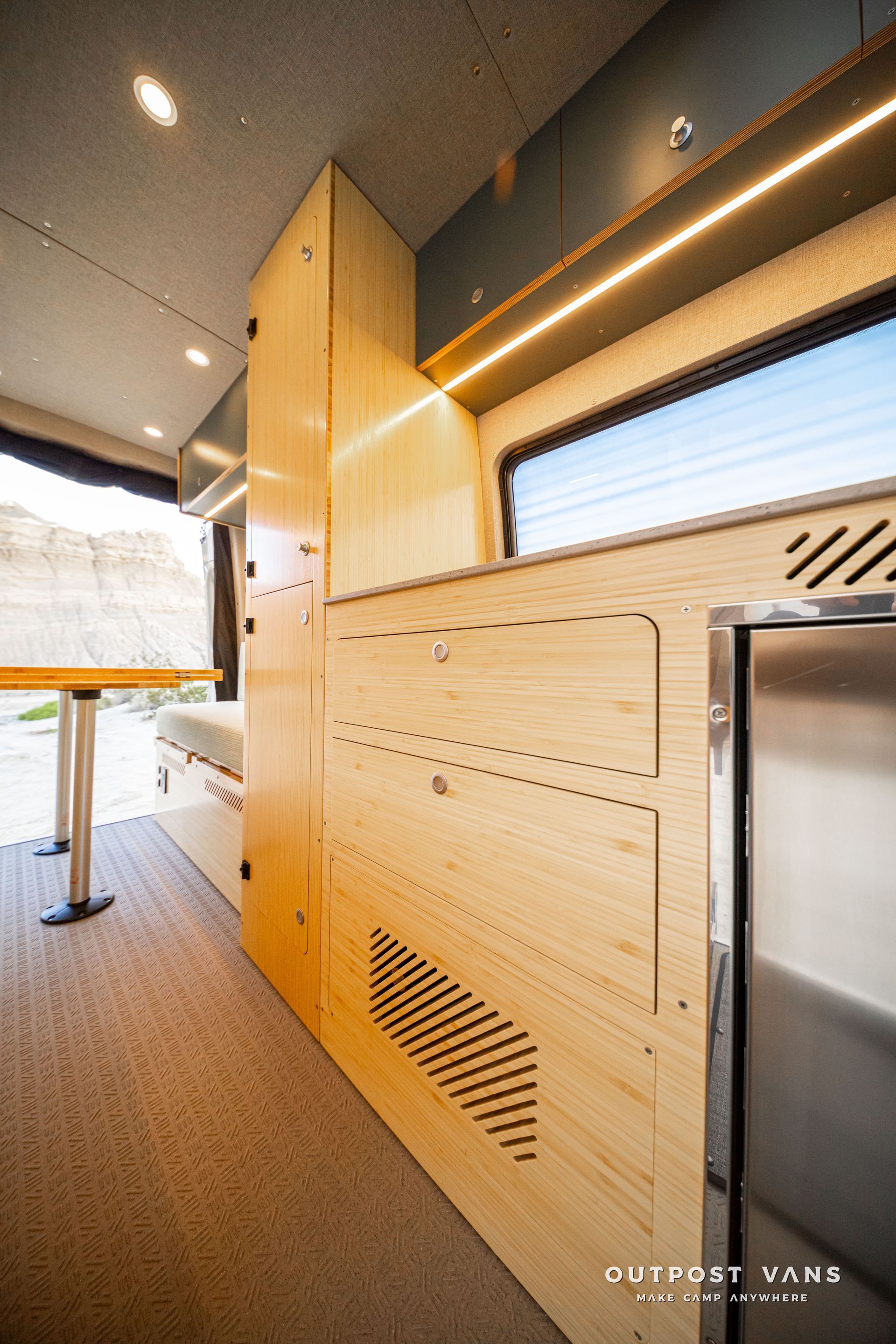 Compact van interior with light wood cabinetry, a countertop, and a side window on a sunny day