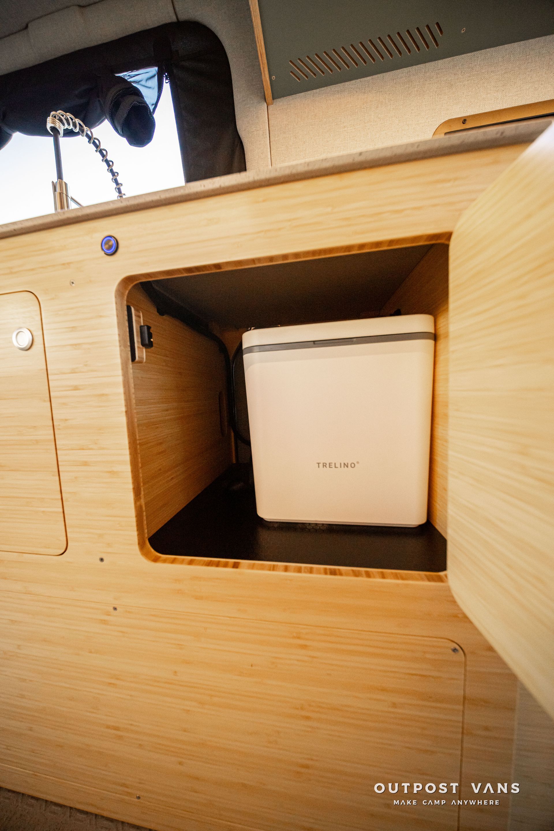 White storage bin inside a wooden cabinet compartment on a boat or RV interior.
