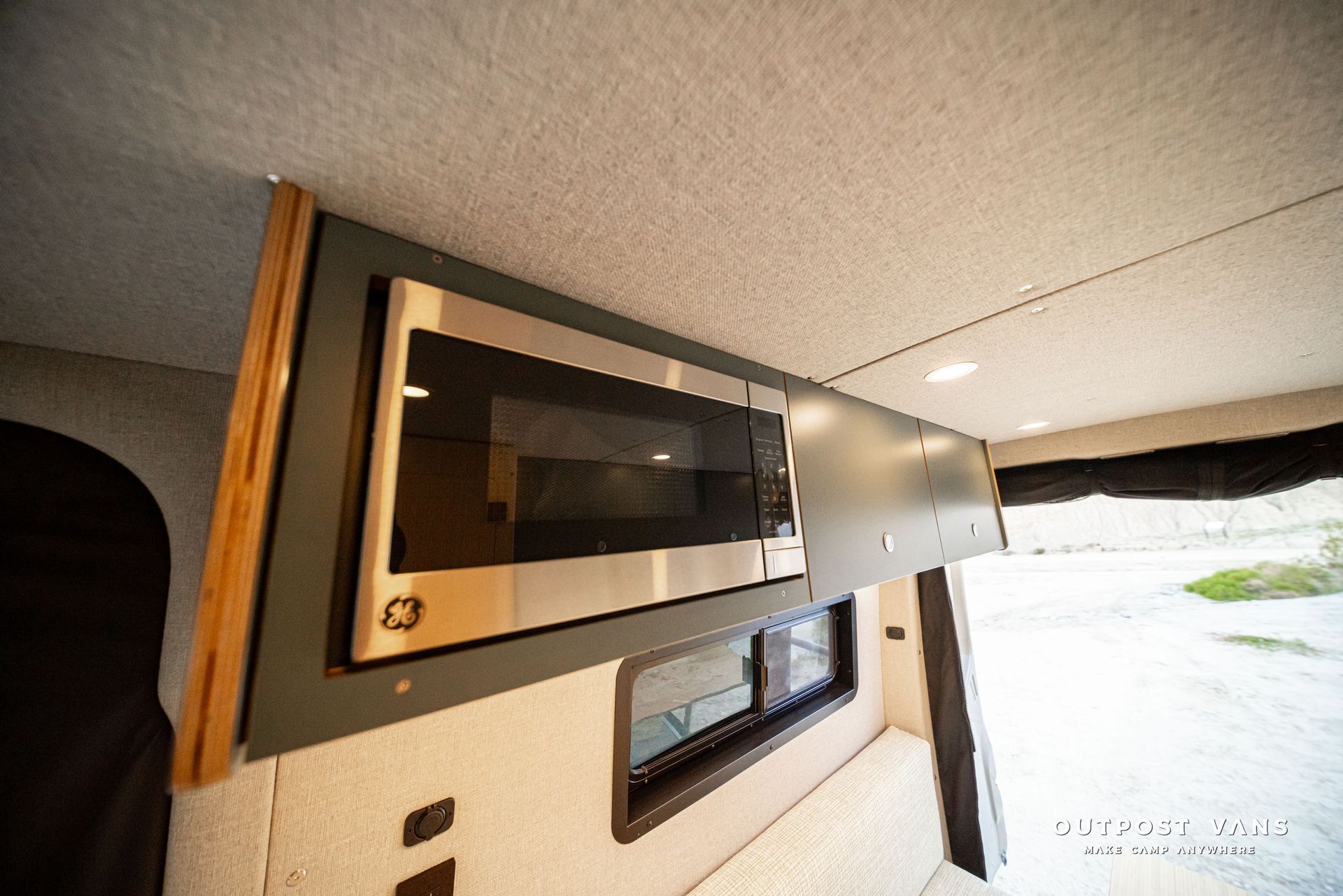 Modern RV interior with built-in microwave and windowed wall panel возле doorway