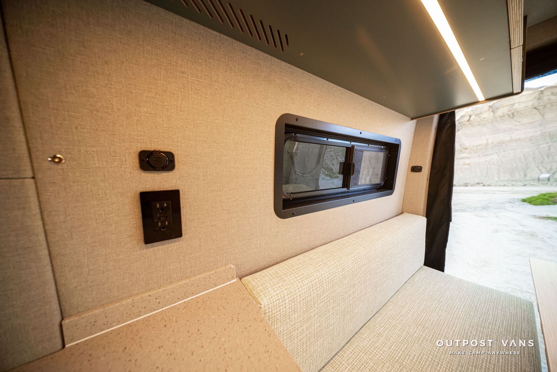 Modern beige interior corridor with wall-mounted buttons and a long narrow window through to the outside