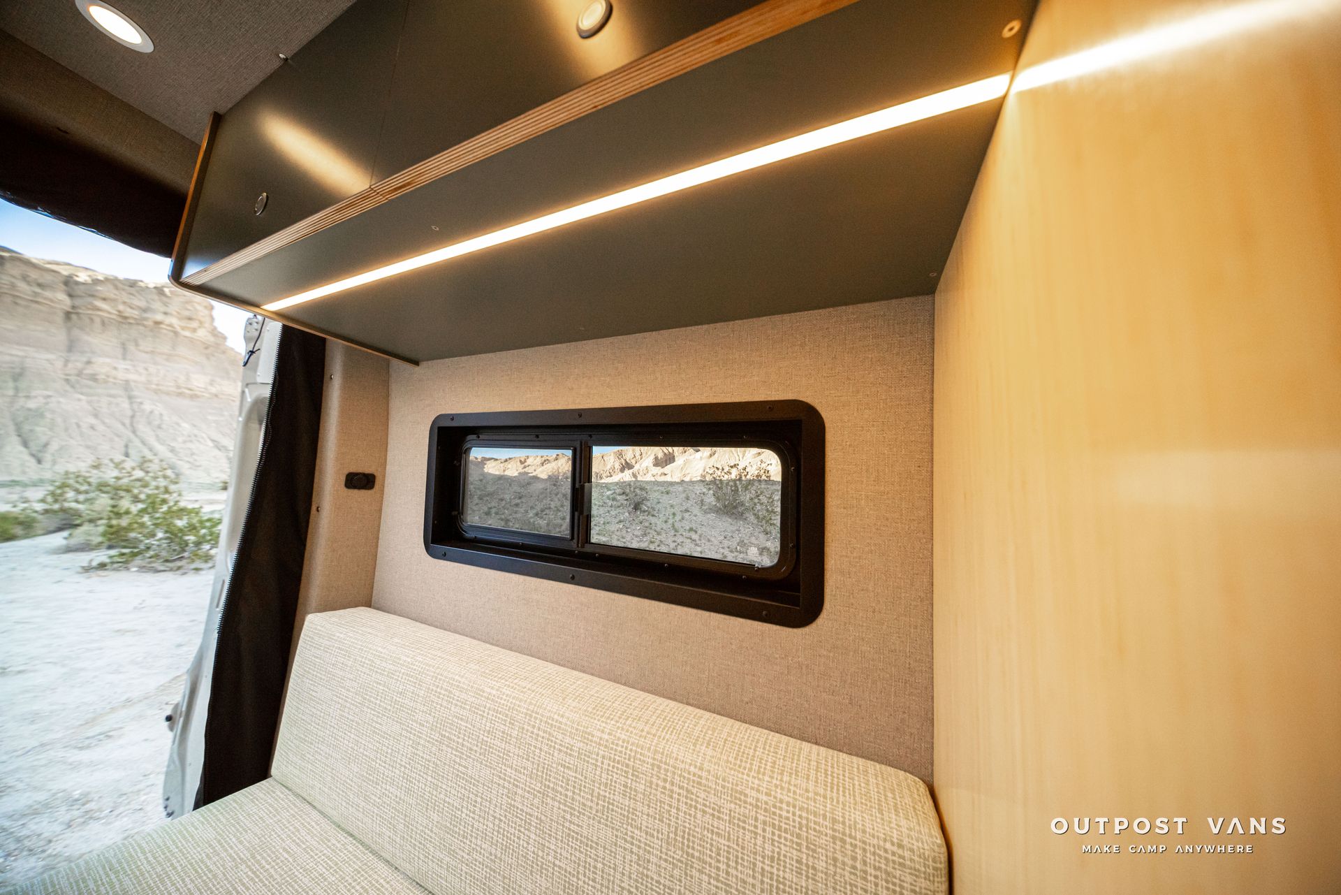 Modern camper van interior with bed, small window, and warm LED ceiling lights