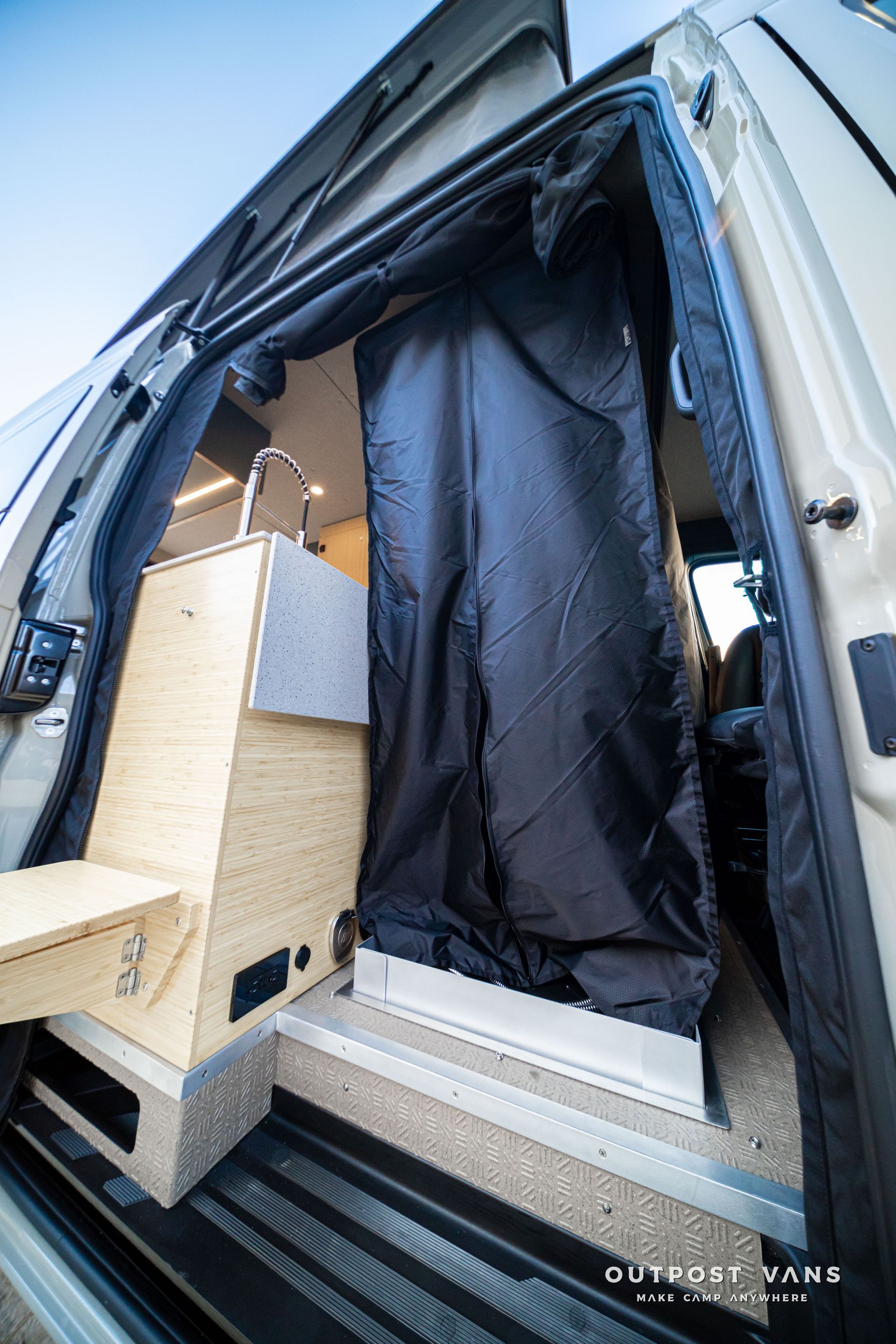 Open van interior with a black curtain, wooden storage boxes, and a built-in step near the sliding door.