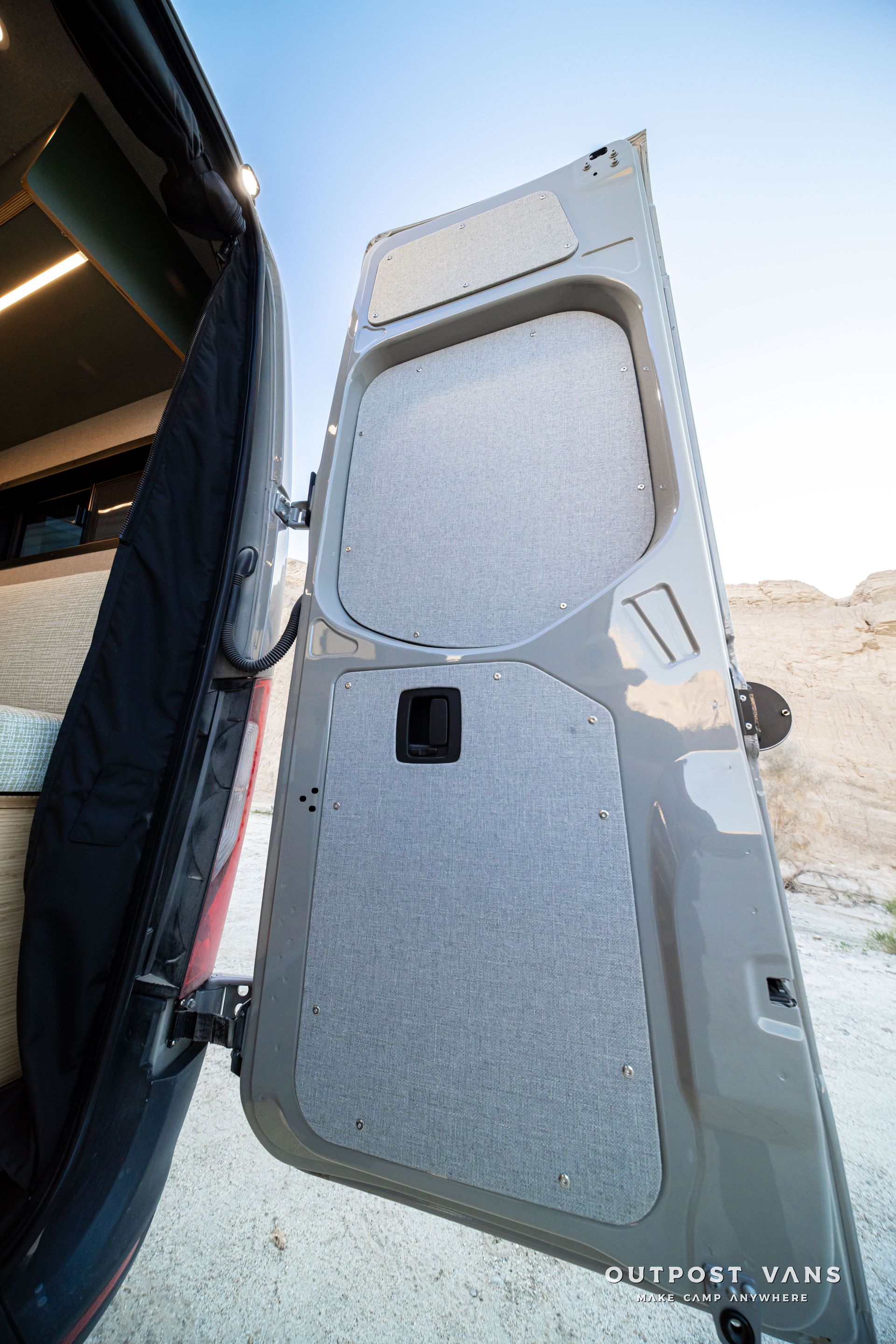 Open van door on a vehicle, showing a gray padded panel inside.