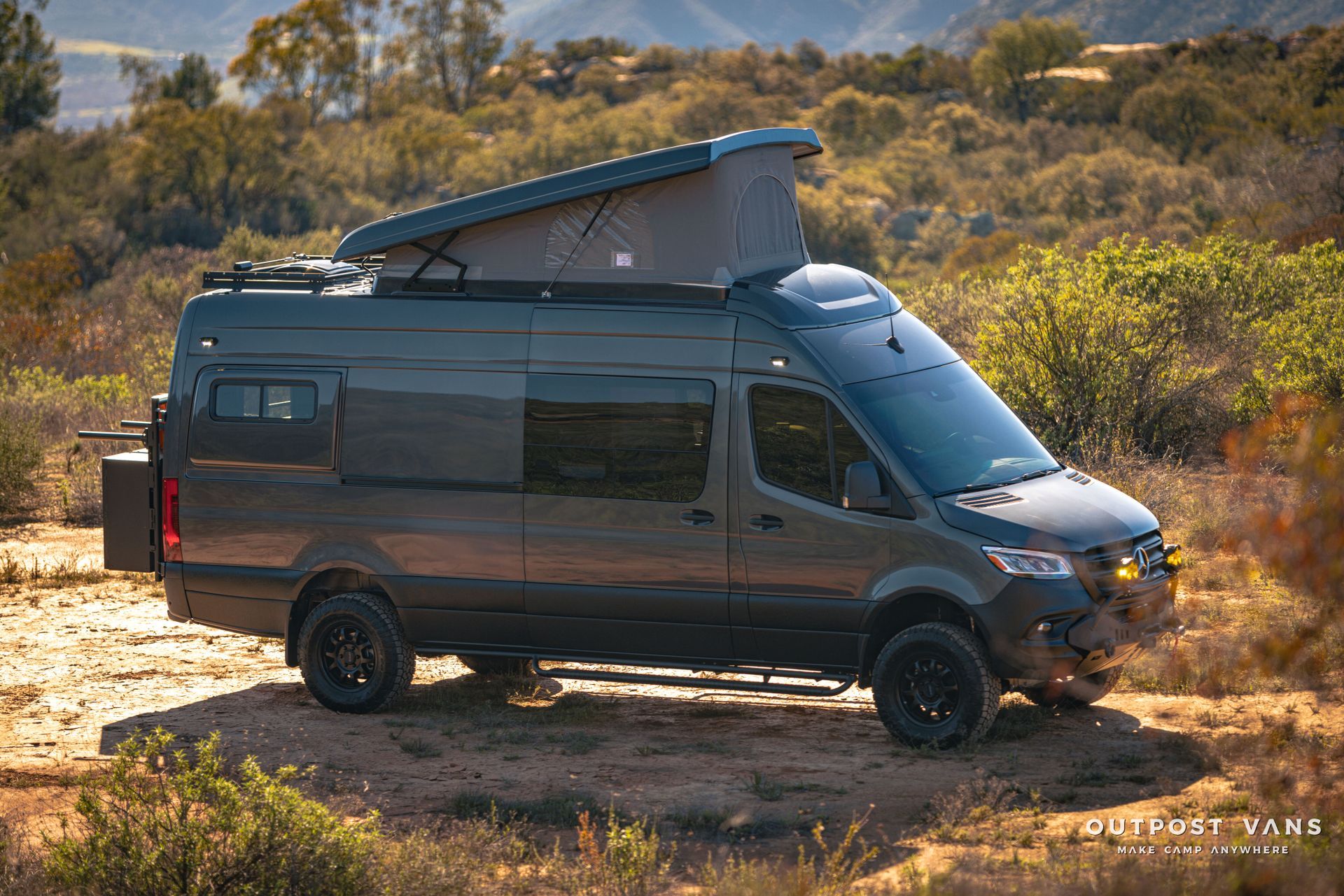 A van with a pop up roof is parked in the middle of a desert.