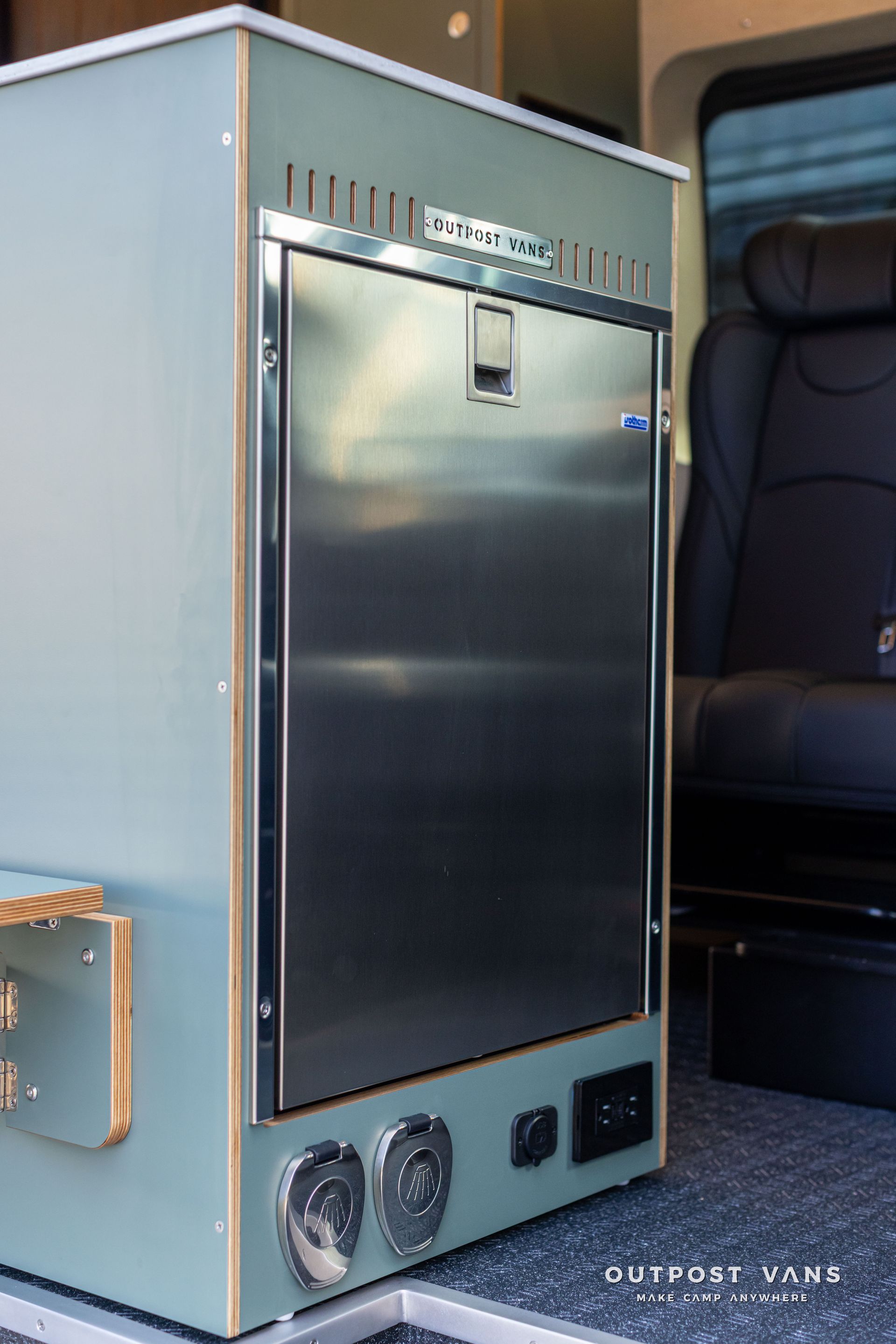 Vintage metal cabinet with a black door and dials, shown inside a vehicle or aircraft cabin