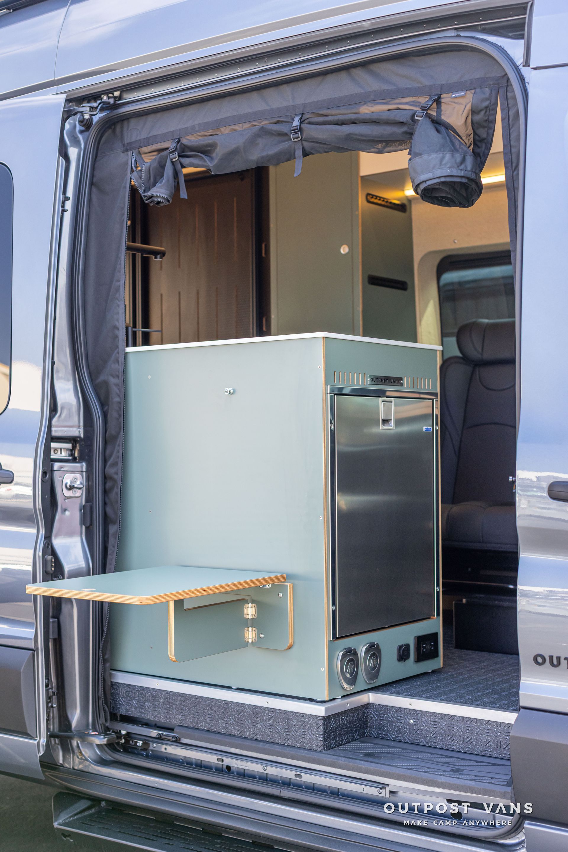 Large gray cabinet being moved into a van through an open side door, with a small step stool nearby