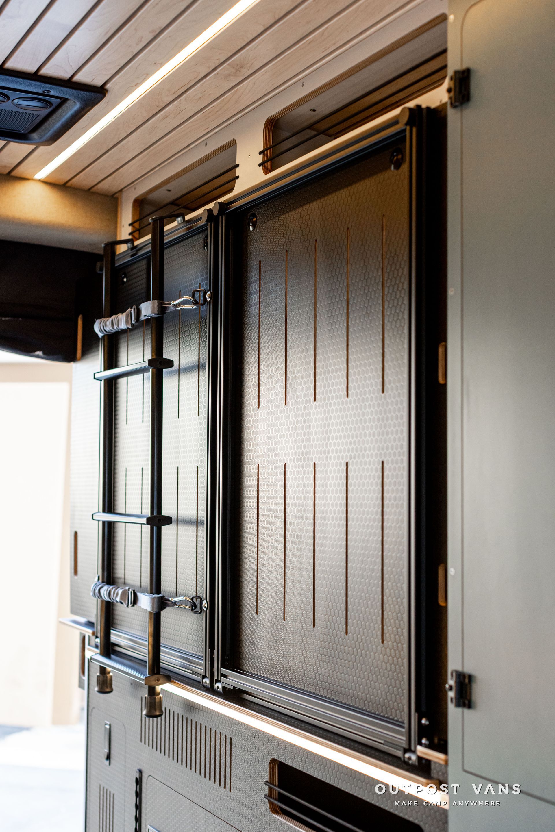 Black metal security door with vertical bars and frosted glass panels beside a wall indoors