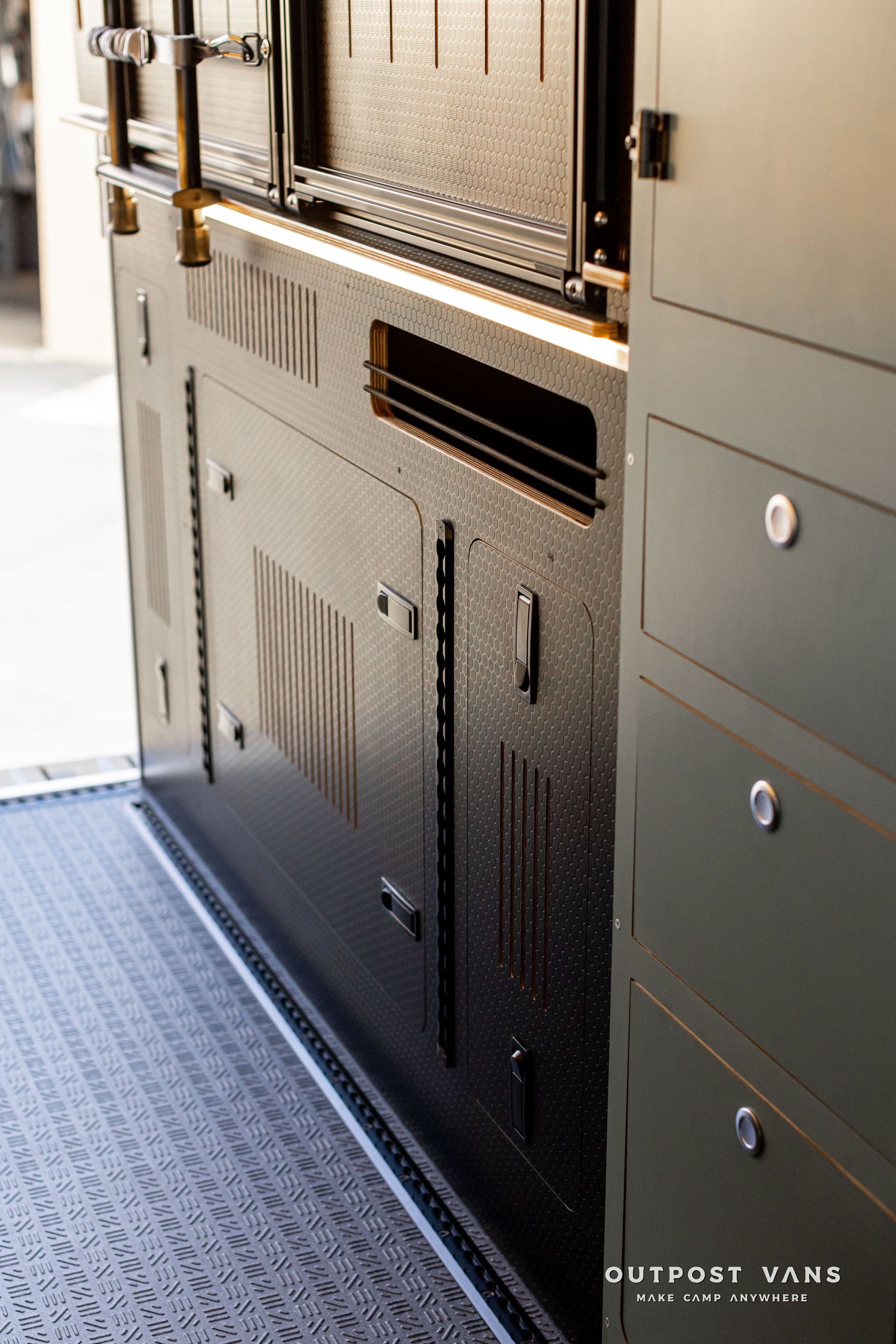 Metal storage cabinet and perforated door panels inside a vehicle or industrial interior with carpeted floor.