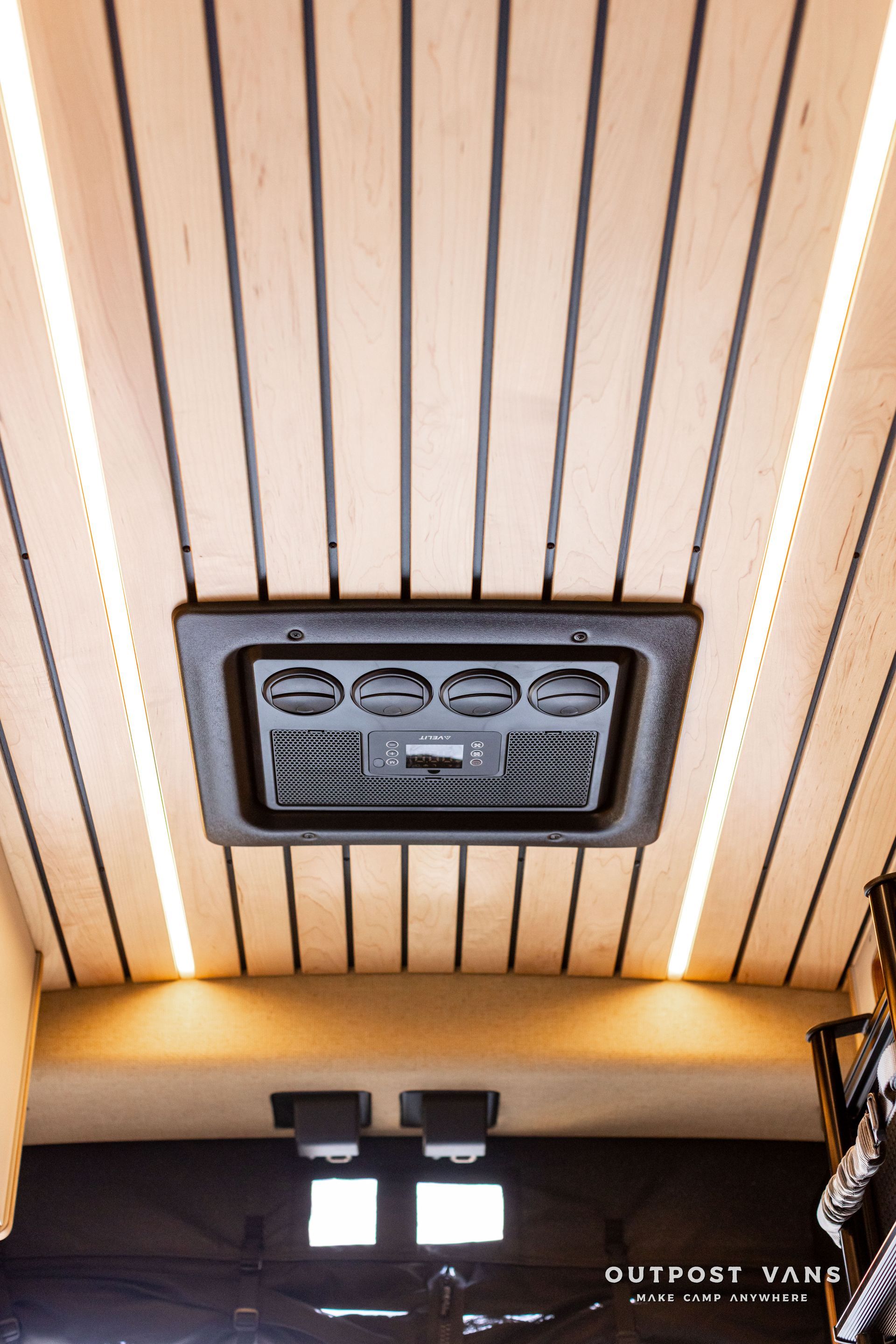Ceiling view with wood slats, a central vent, and warm lights in an indoor space