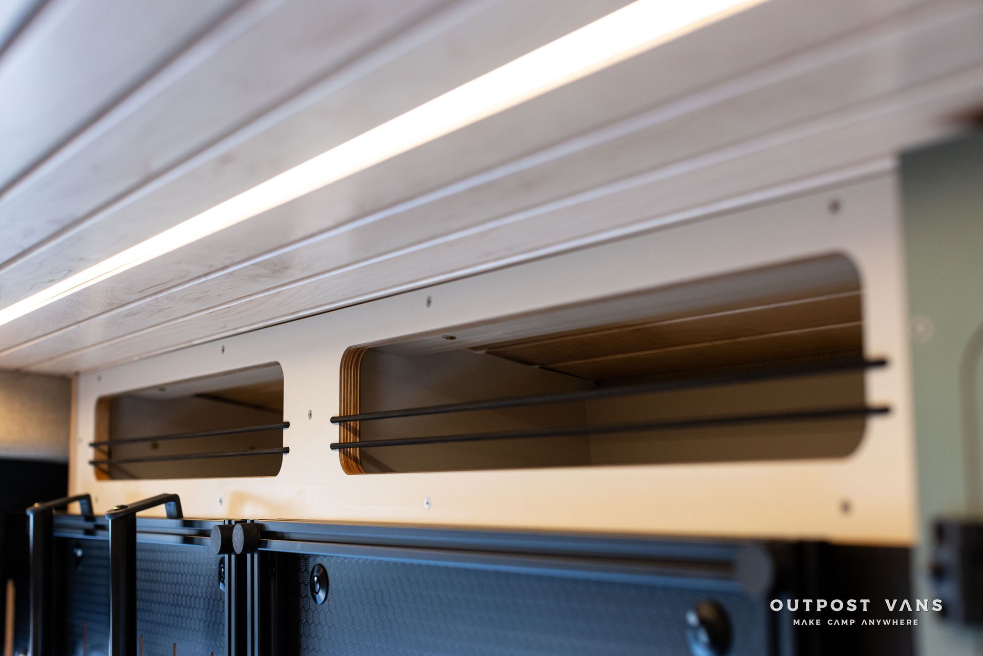 Interior of a train car with luggage racks and overhead ventilation vents above blue seats