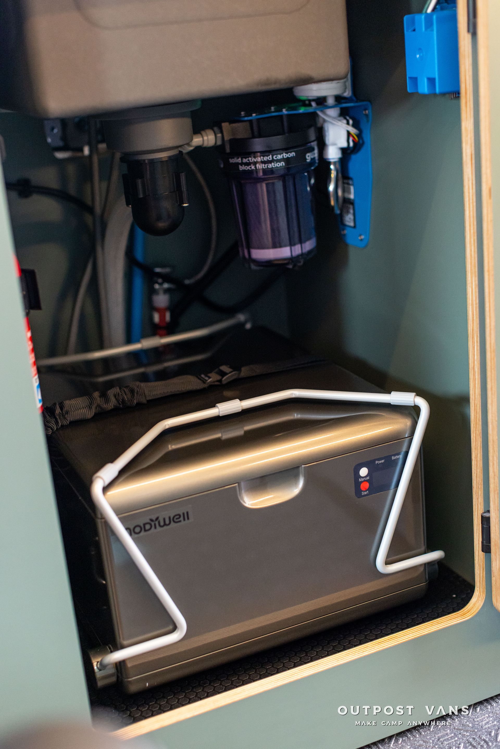 Under-sink water filtration unit with gray and blue components inside a cabinet