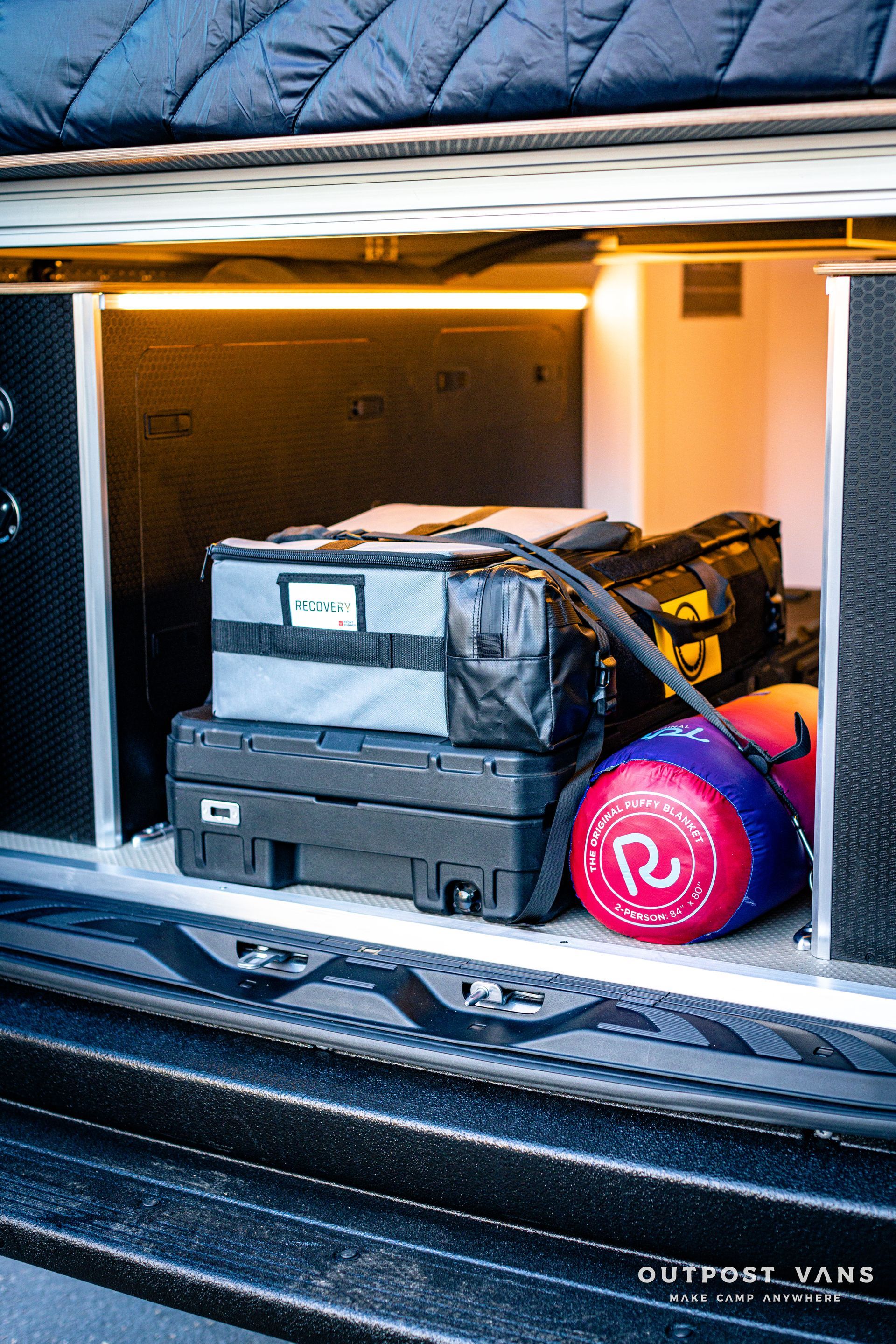 the back of a van with a bunch of luggage in it .