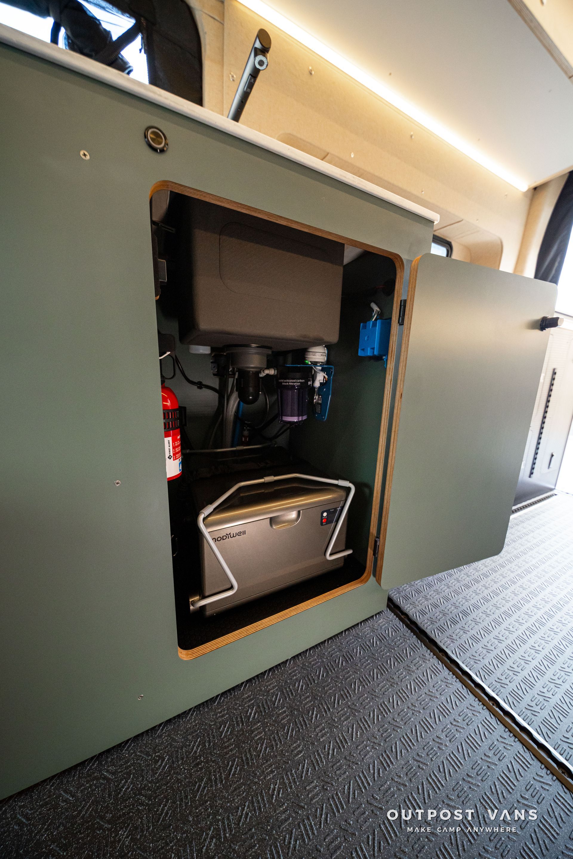 Open cabinet with electronics and a small amplifier inside, mounted in a vehicle or trailer interior.