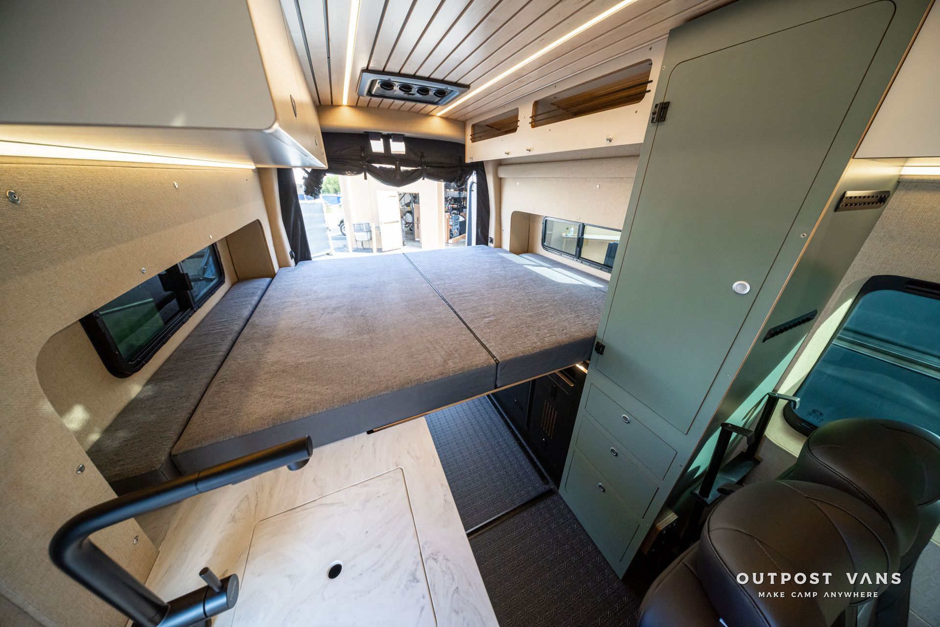 Interior of a van with a fold-out bed platform, cabinet, and compact camper-style layout