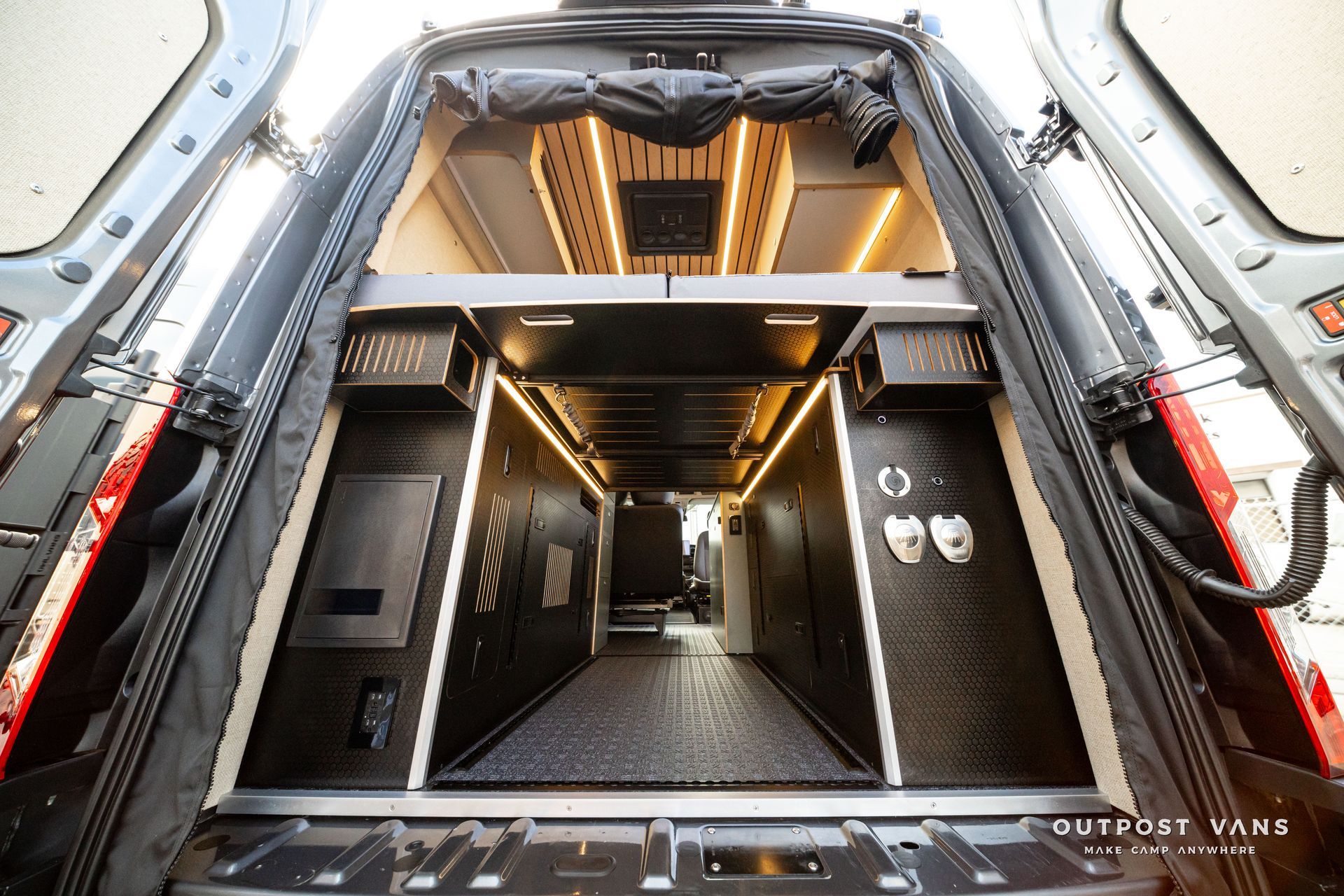 Interior of a futuristic black-and-silver transport van with an illuminated central aisle and equipment panels