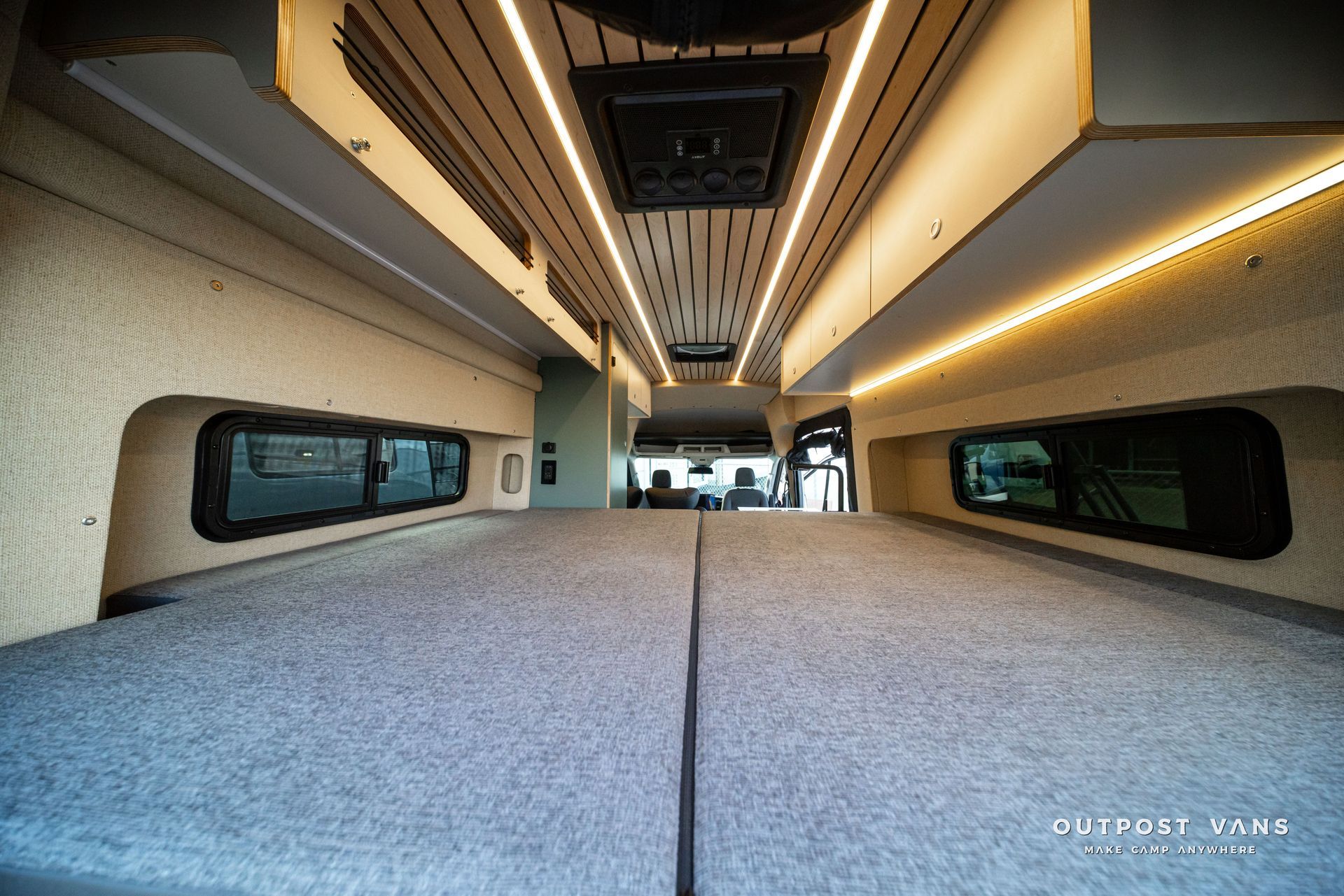 Modern van interior with gray bench seats, panoramic windows, and warm ceiling lights