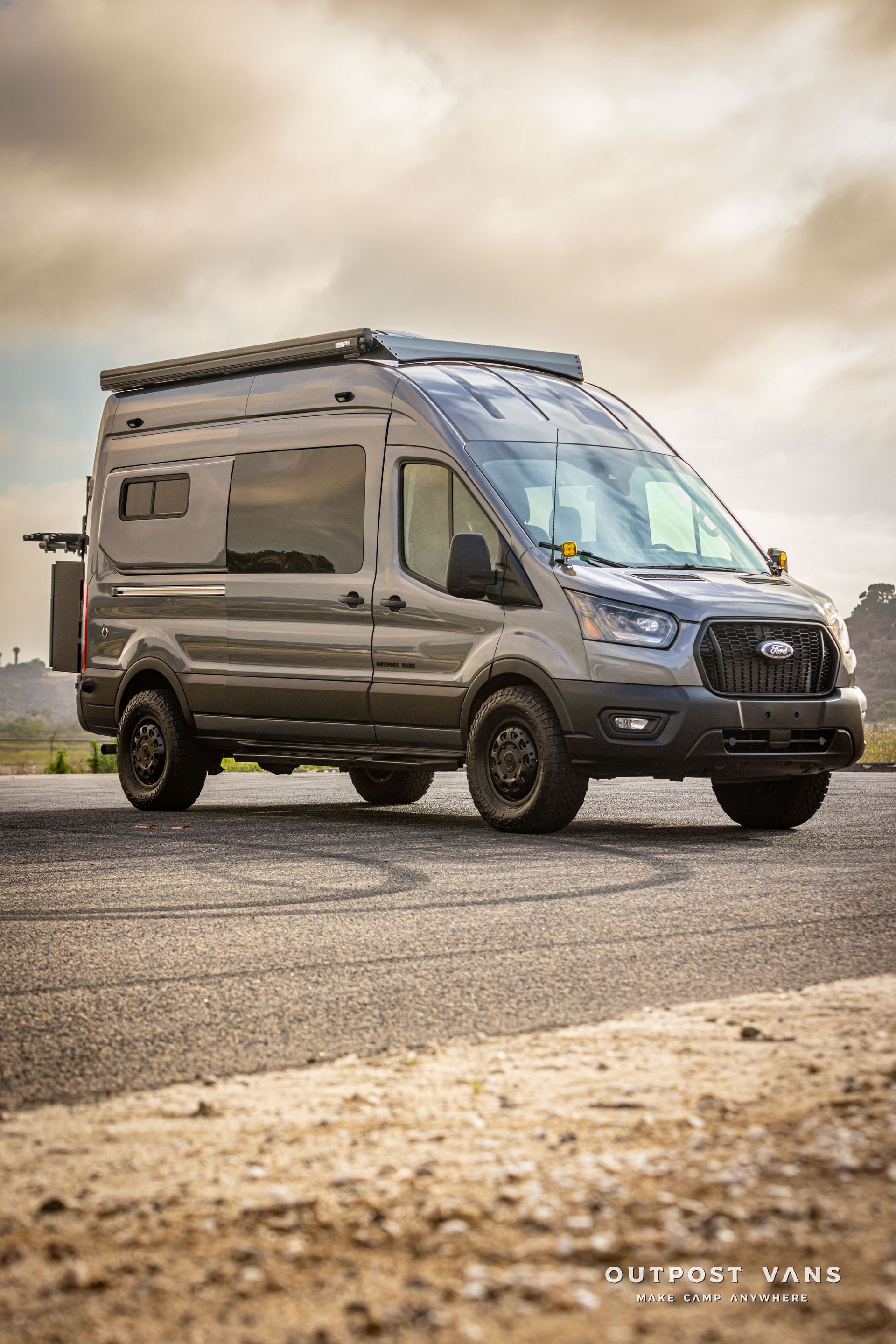 Shimmer Gray camper van parked on a gravel road under a cloudy sky