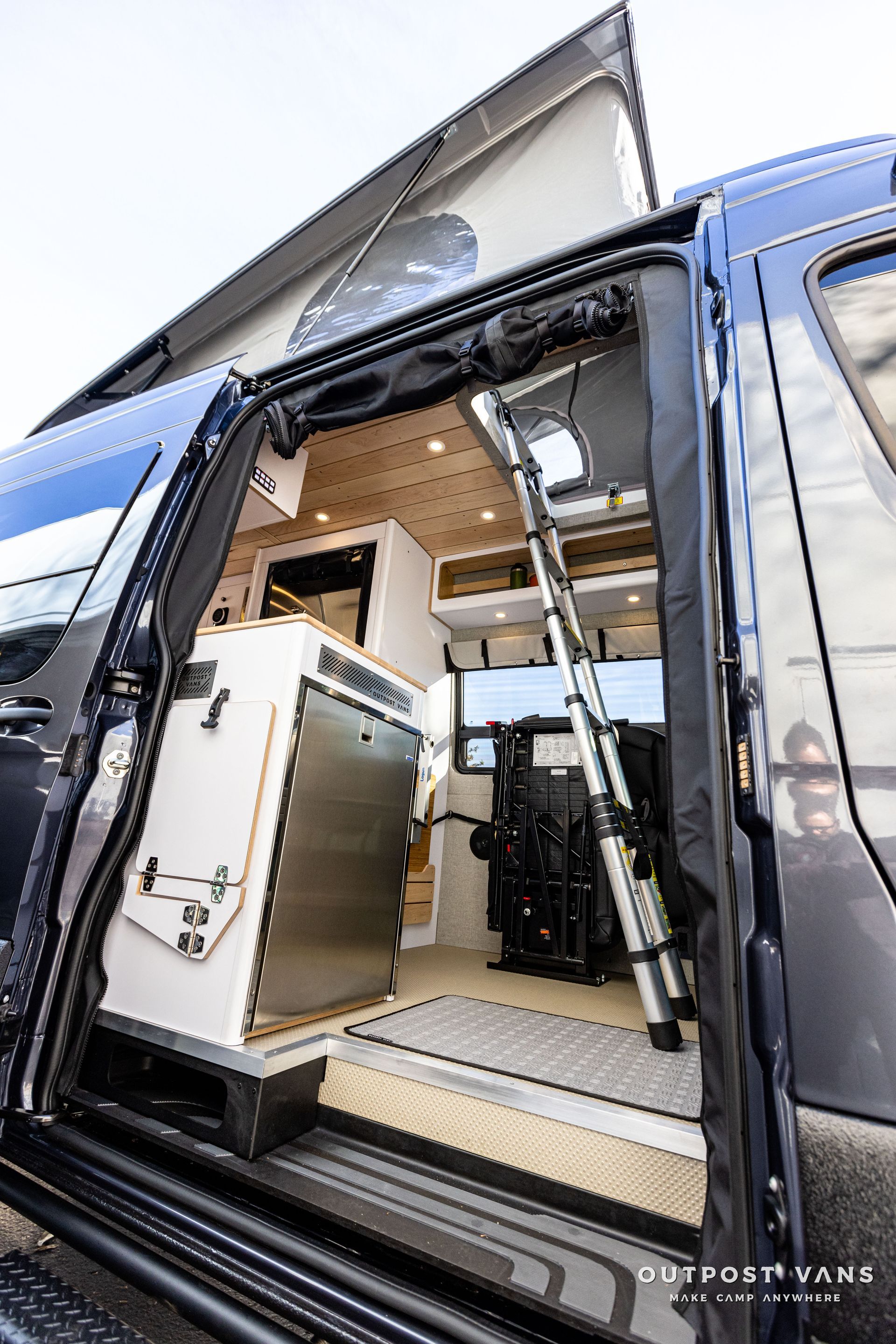 the inside of a camper van with the door open and a ladder .