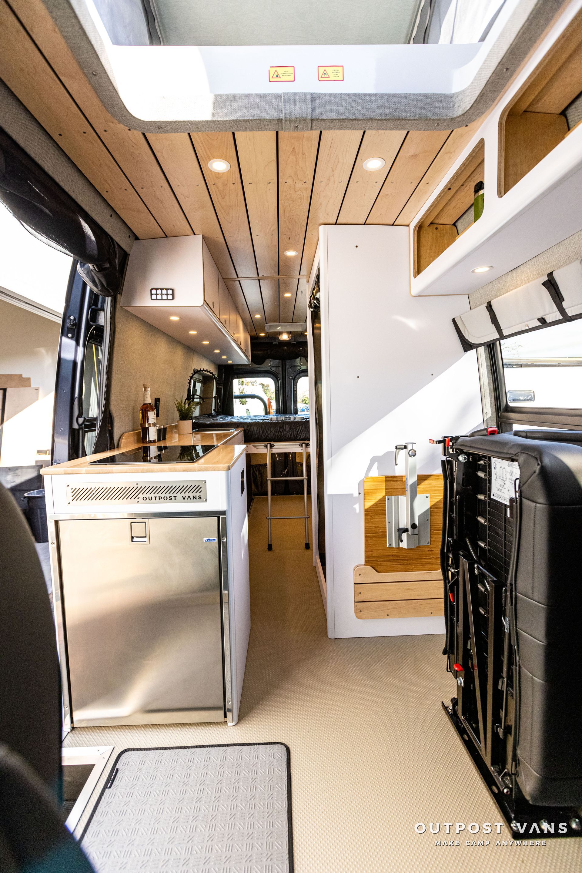 the inside of a camper van with a kitchen and stainless steel appliances .