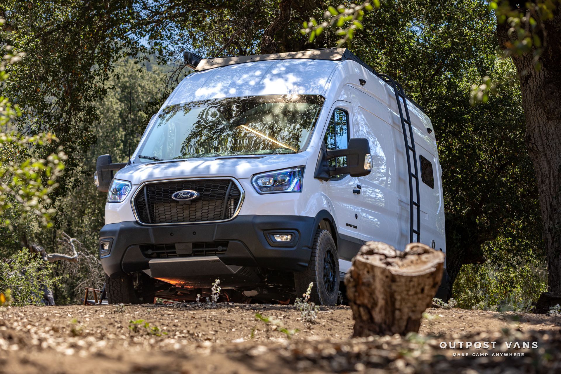White camper van navigating rocky trail in a wooded area