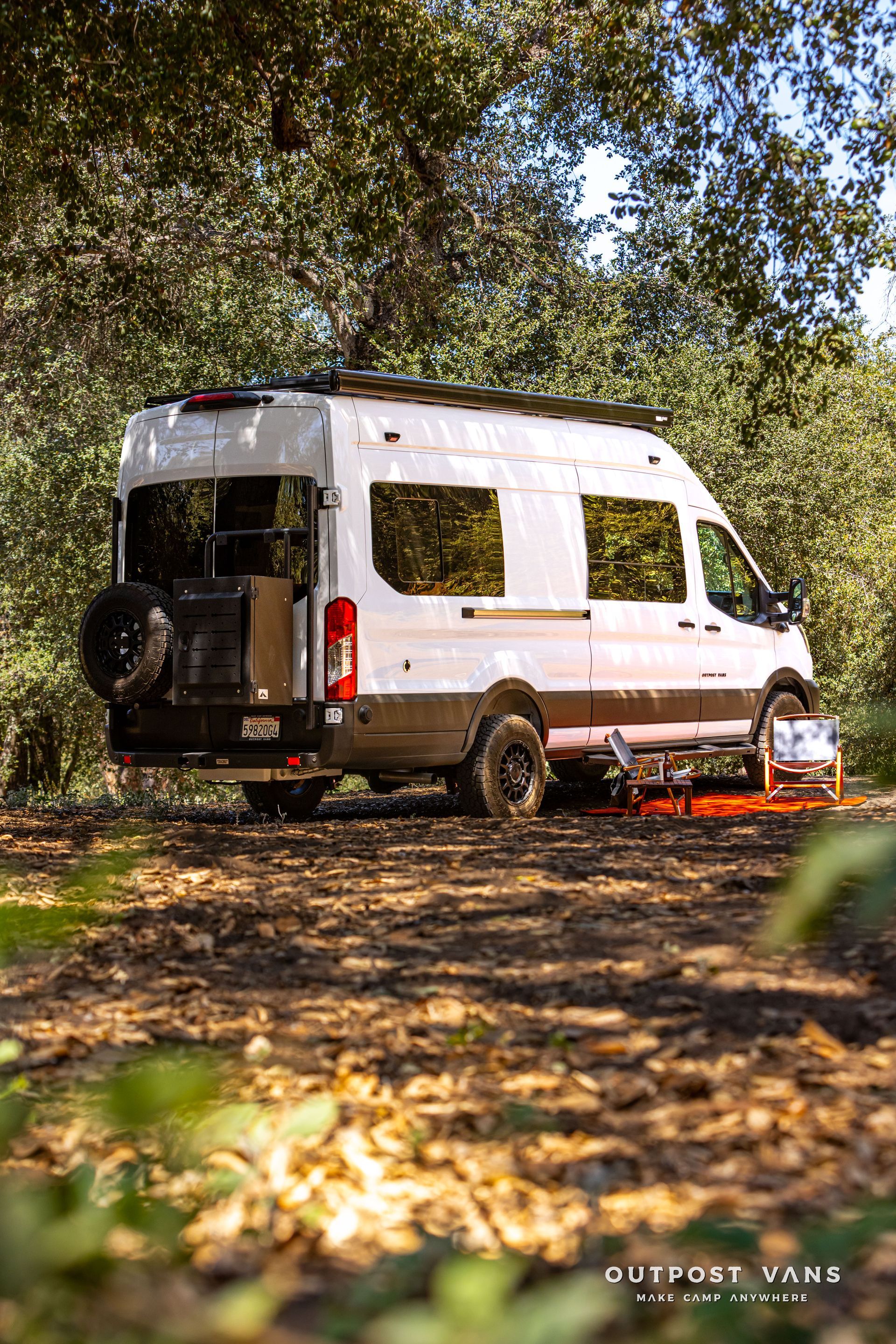 White camper van parked in a leafy forest clearing