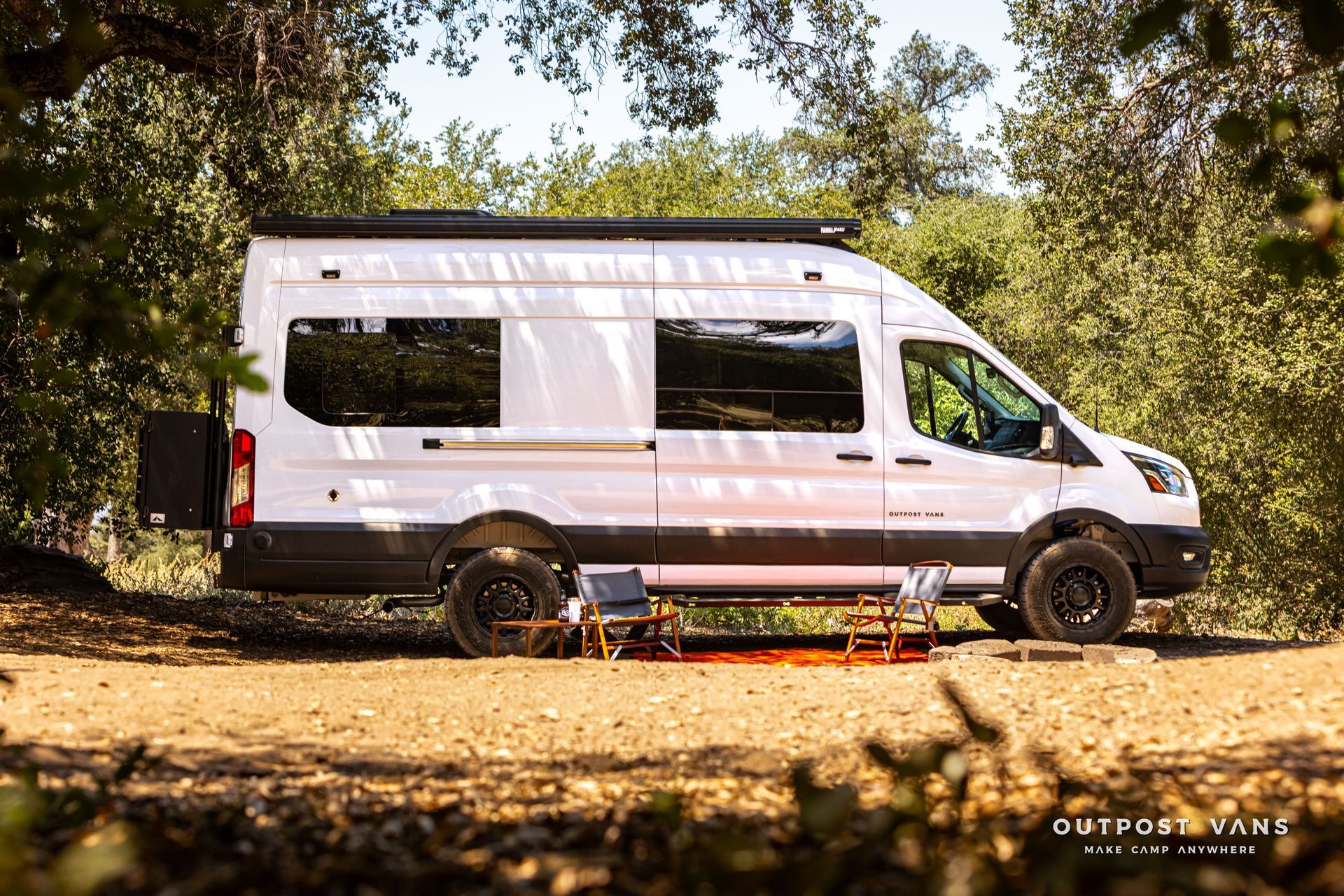 White van with pop-up roof parked on a dirt road in a wooded area