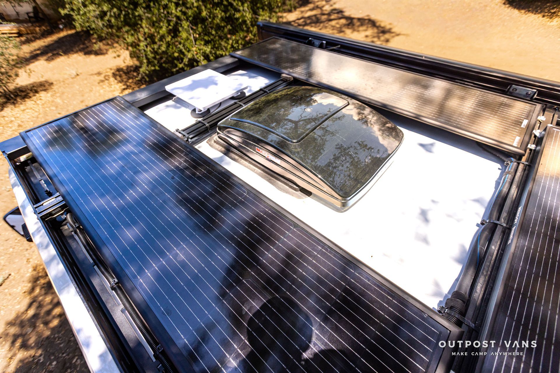 Solar roof panels surrounding a skylight on a modern rooftop, viewed from above.