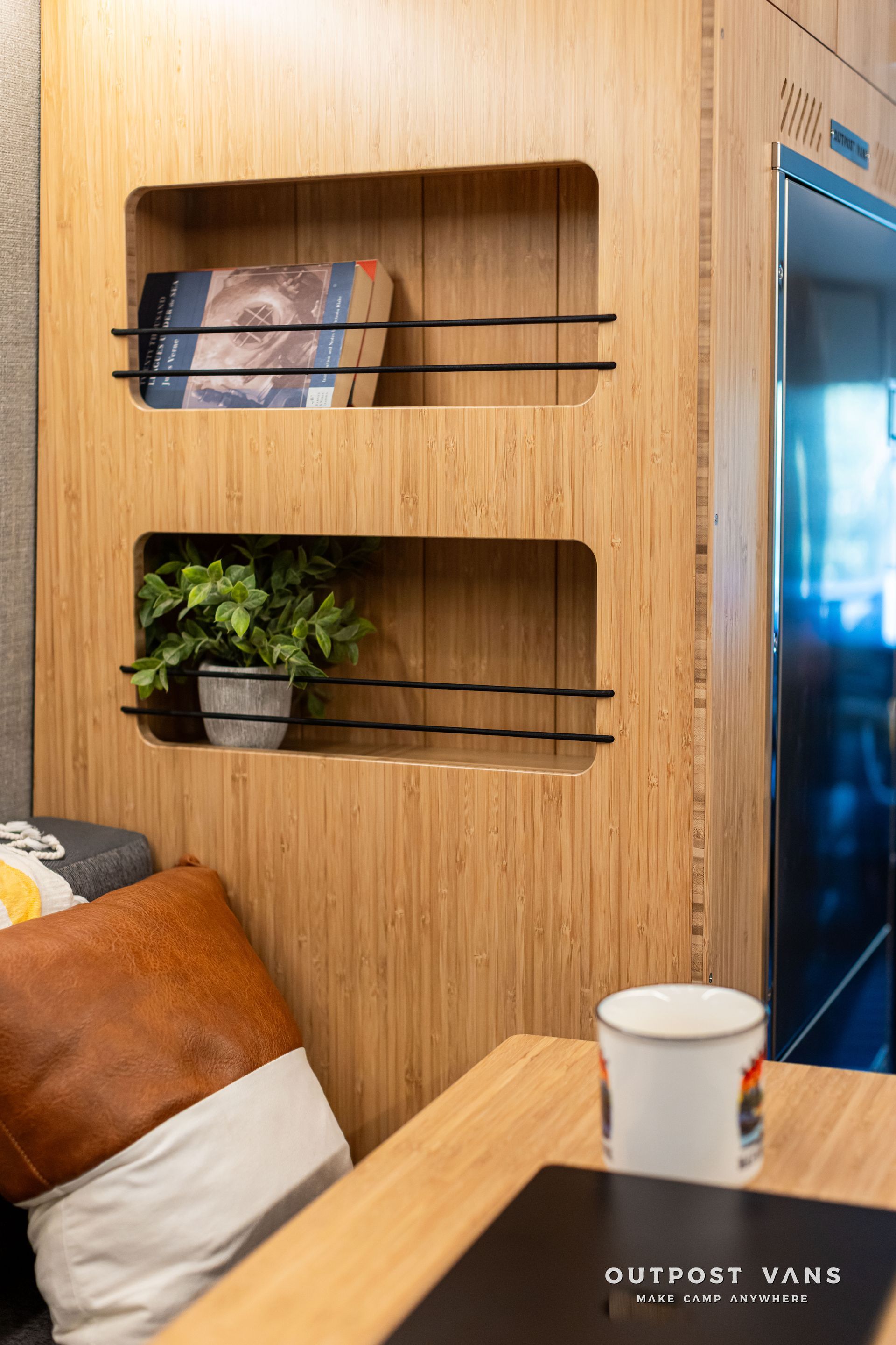 Wood-paneled wall with built-in shelves, plants, and a cushioned seating area beside a window.