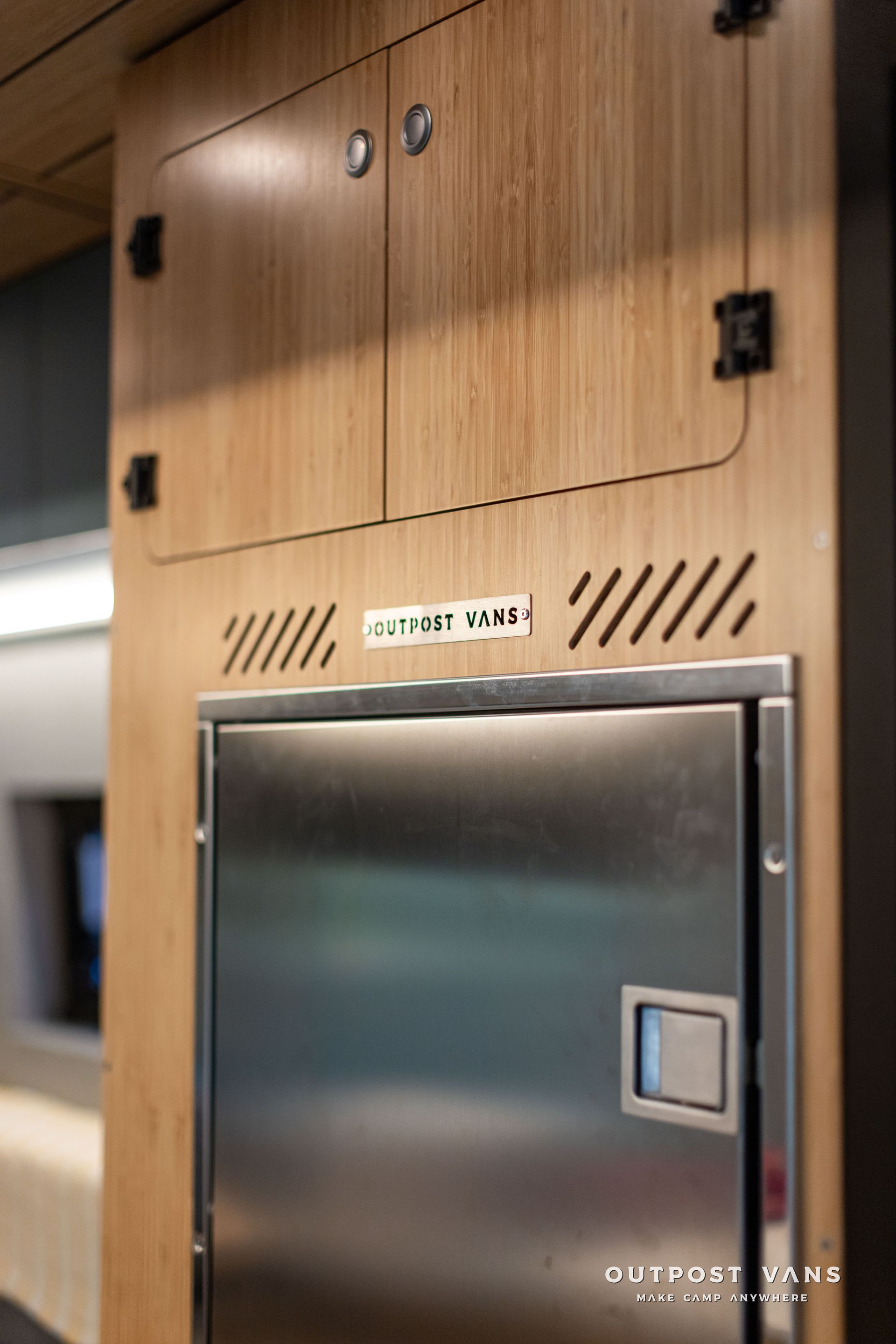 Wood-paneled cabinet with a metal access door and vent slots in an indoor setting