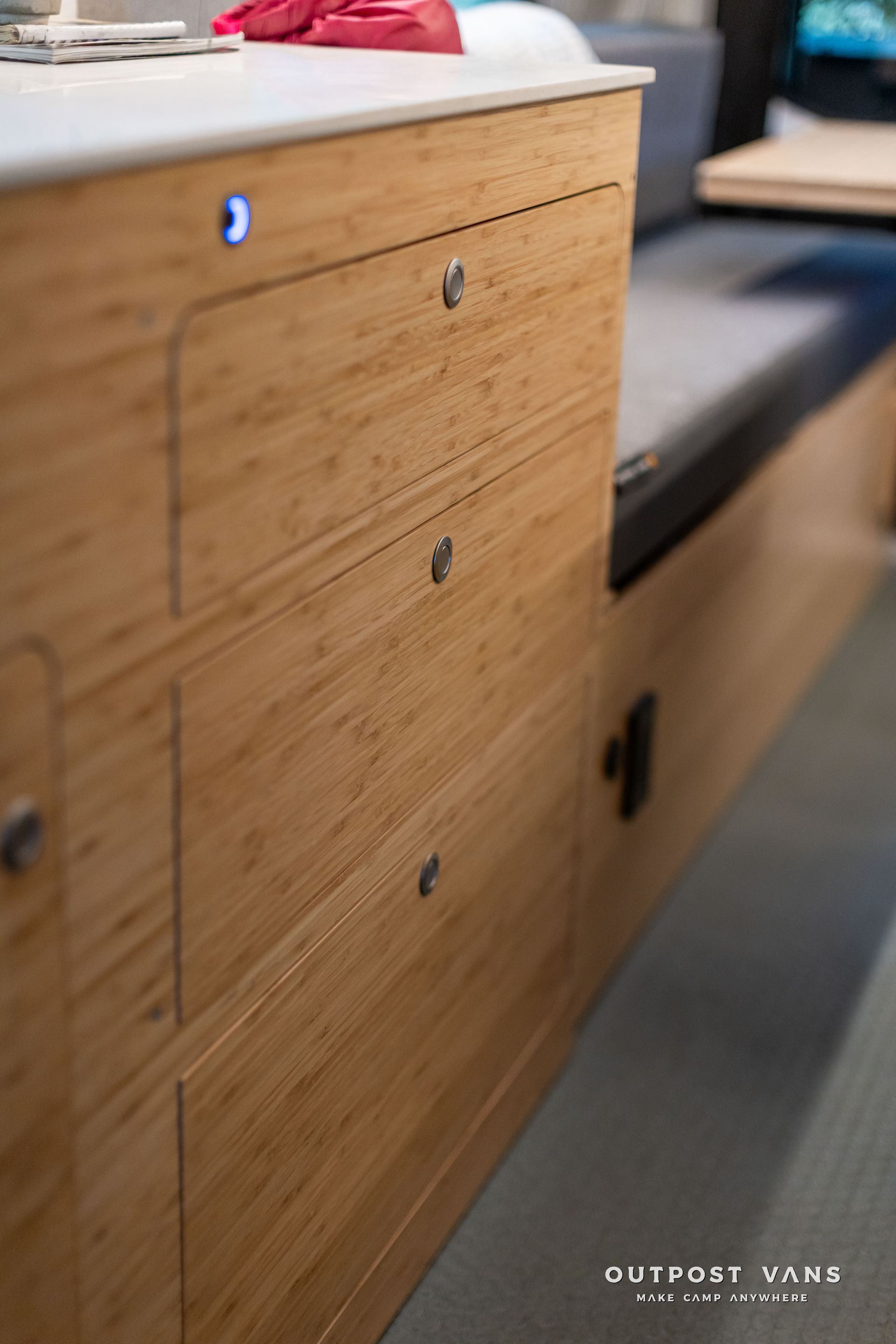 Wood-paneled built-in bench with drawers and black cushion in a modern interior