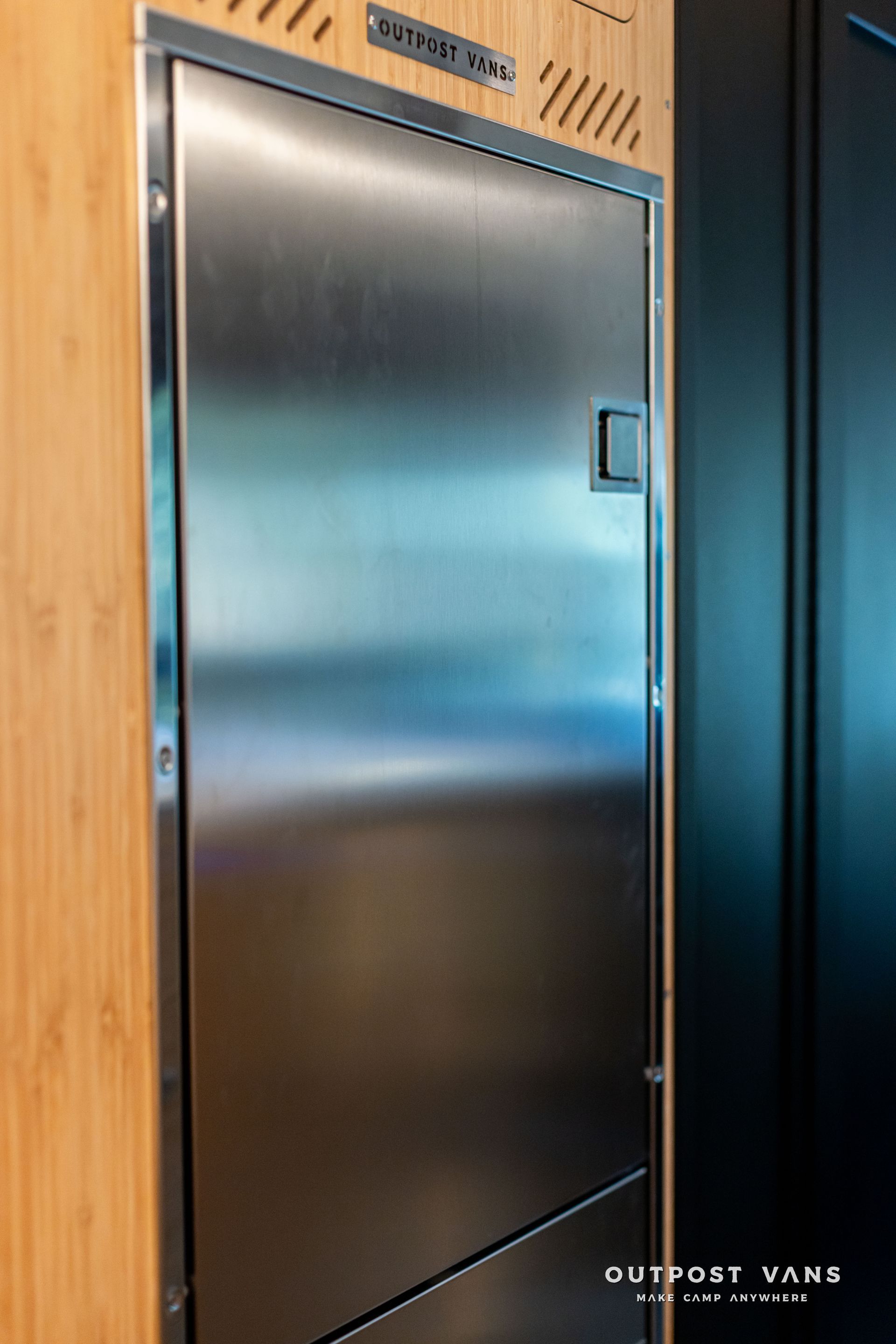 Stainless steel door in a wood-paneled interior wall with black trim
