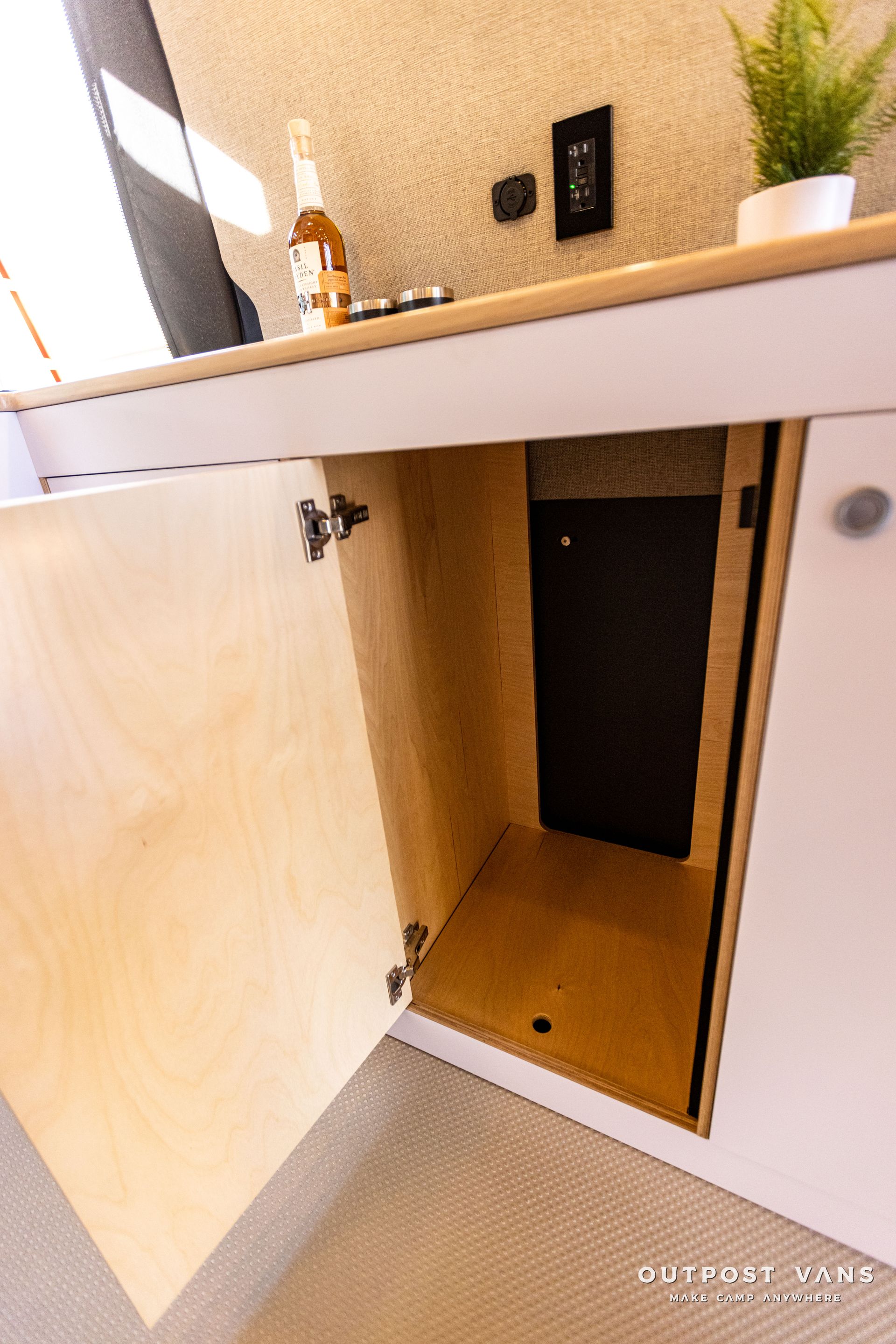 a cabinet with the door open and a bottle of beer in it .