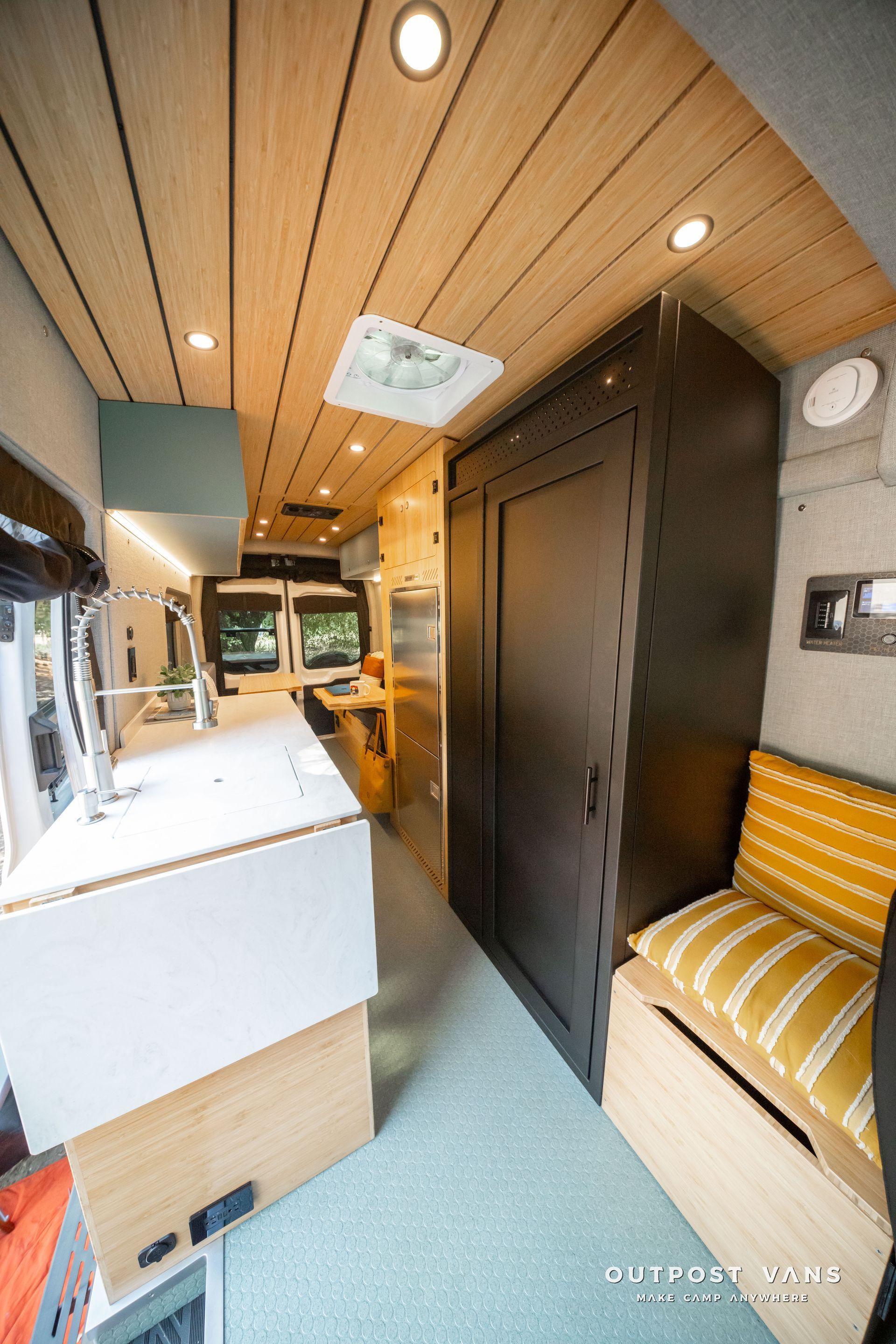 Modern RV interior with wood ceiling, white counters, dark cabinets, and striped bench seating