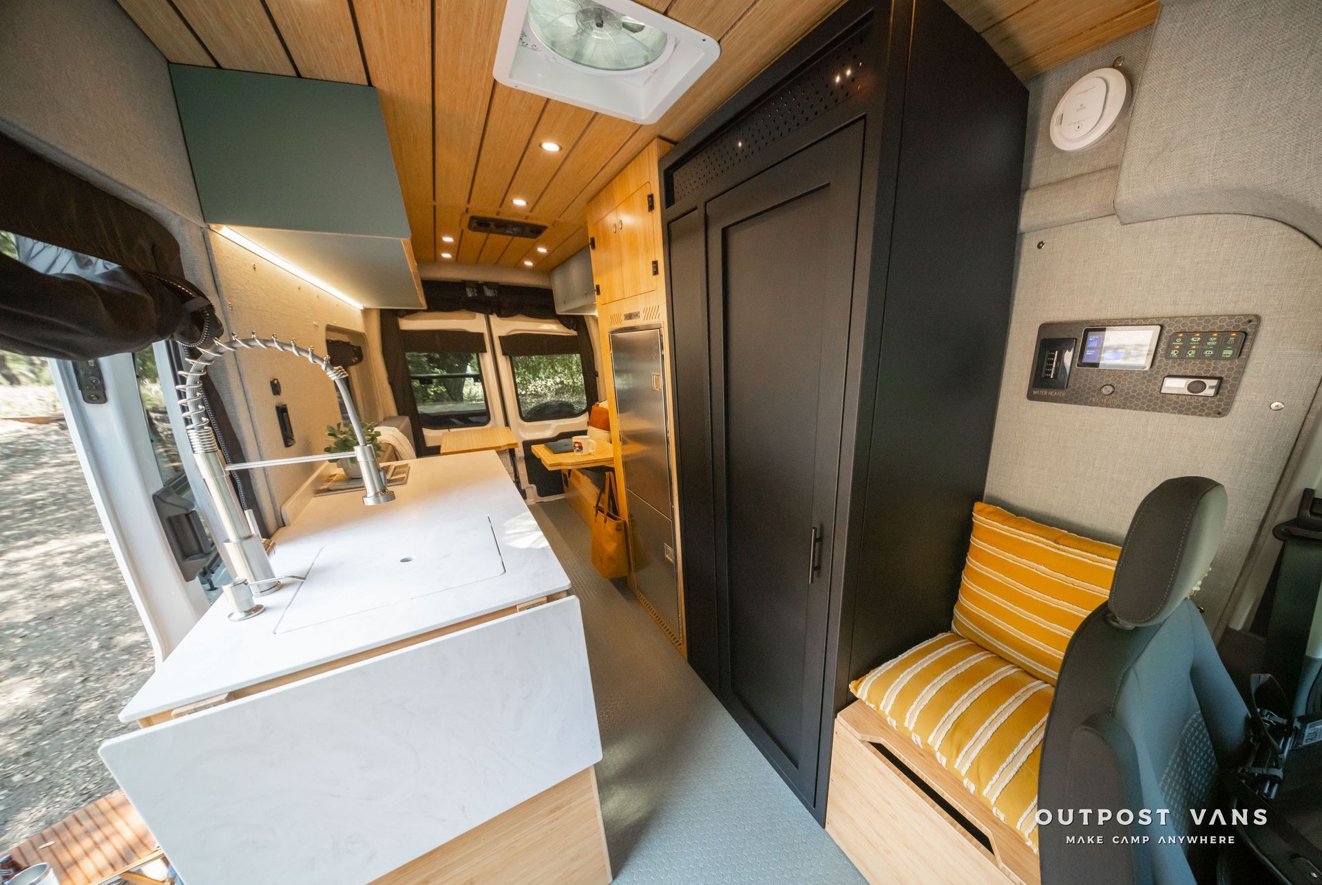 Modern van interior with wood ceiling, white counter, black cabinet, and yellow bench seating