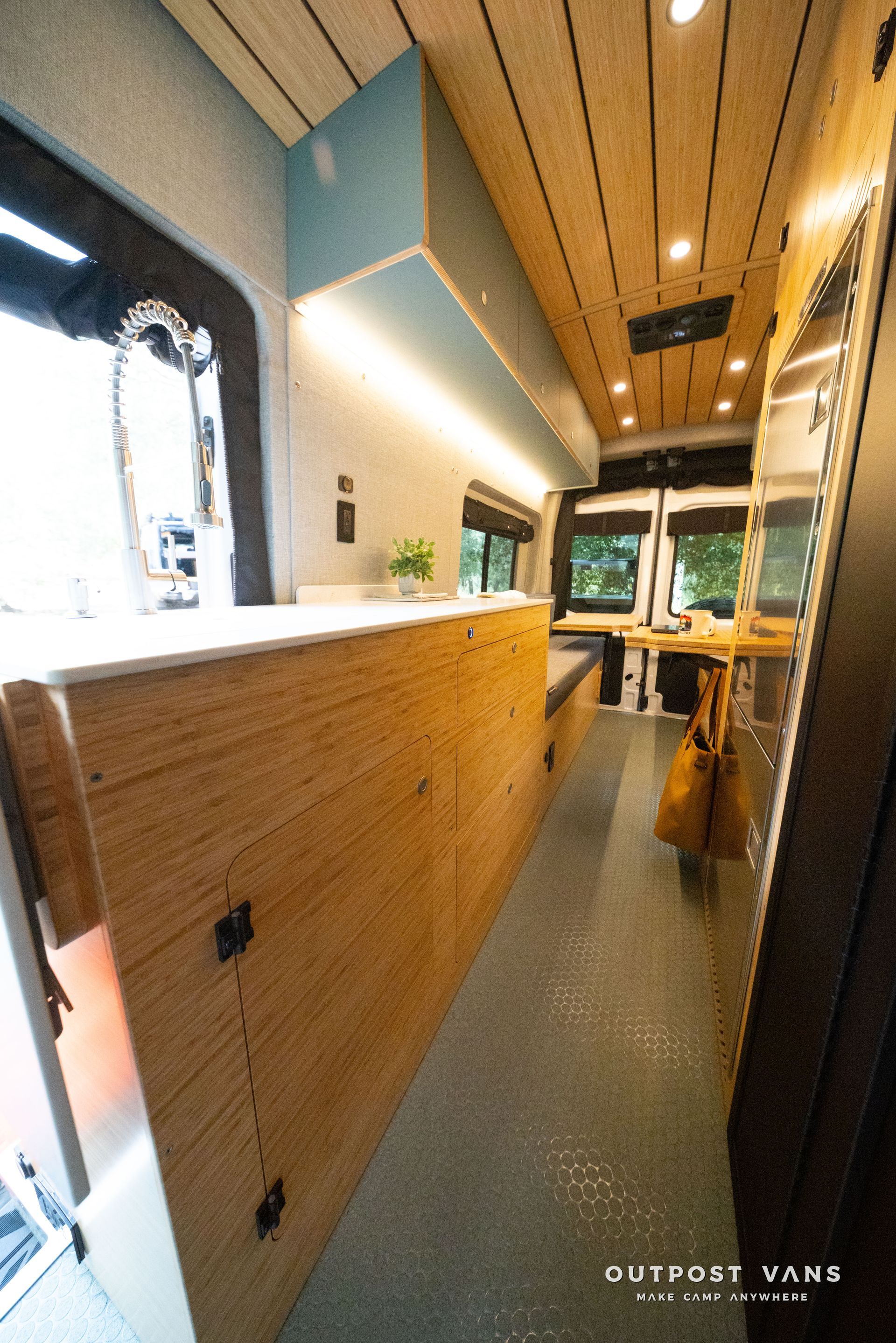 Modern café interior with wooden counter, narrow aisle, and seating near large windows