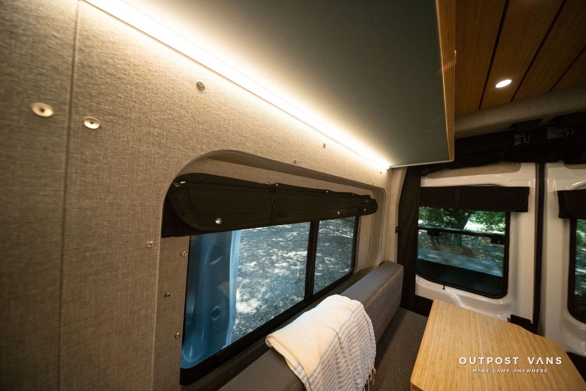 Interior of a modern RV or camper with a bed, window, and warm ambient lighting.